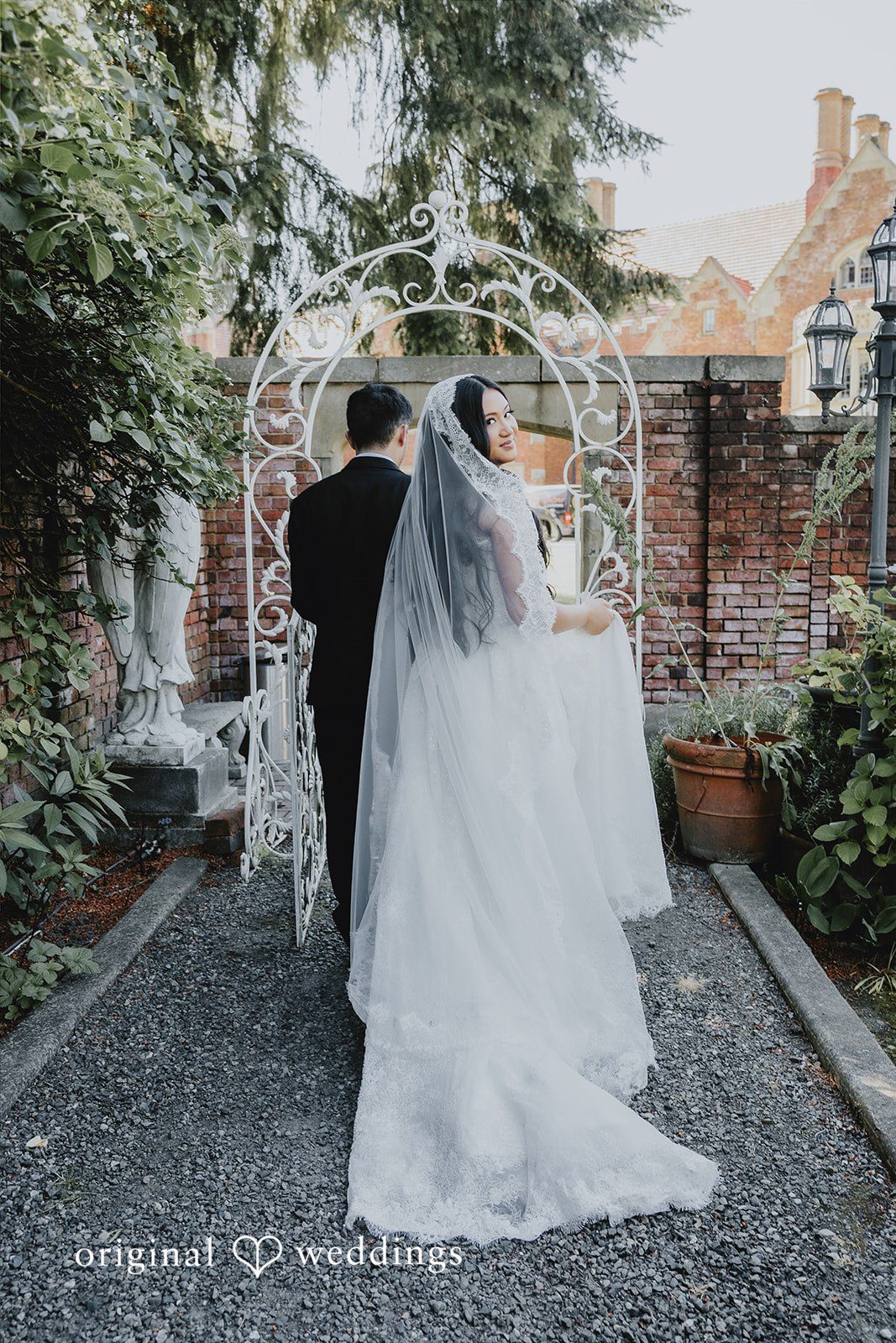 Sharmaine + Ronald A bride and groom walking away together toward a white garden archway.