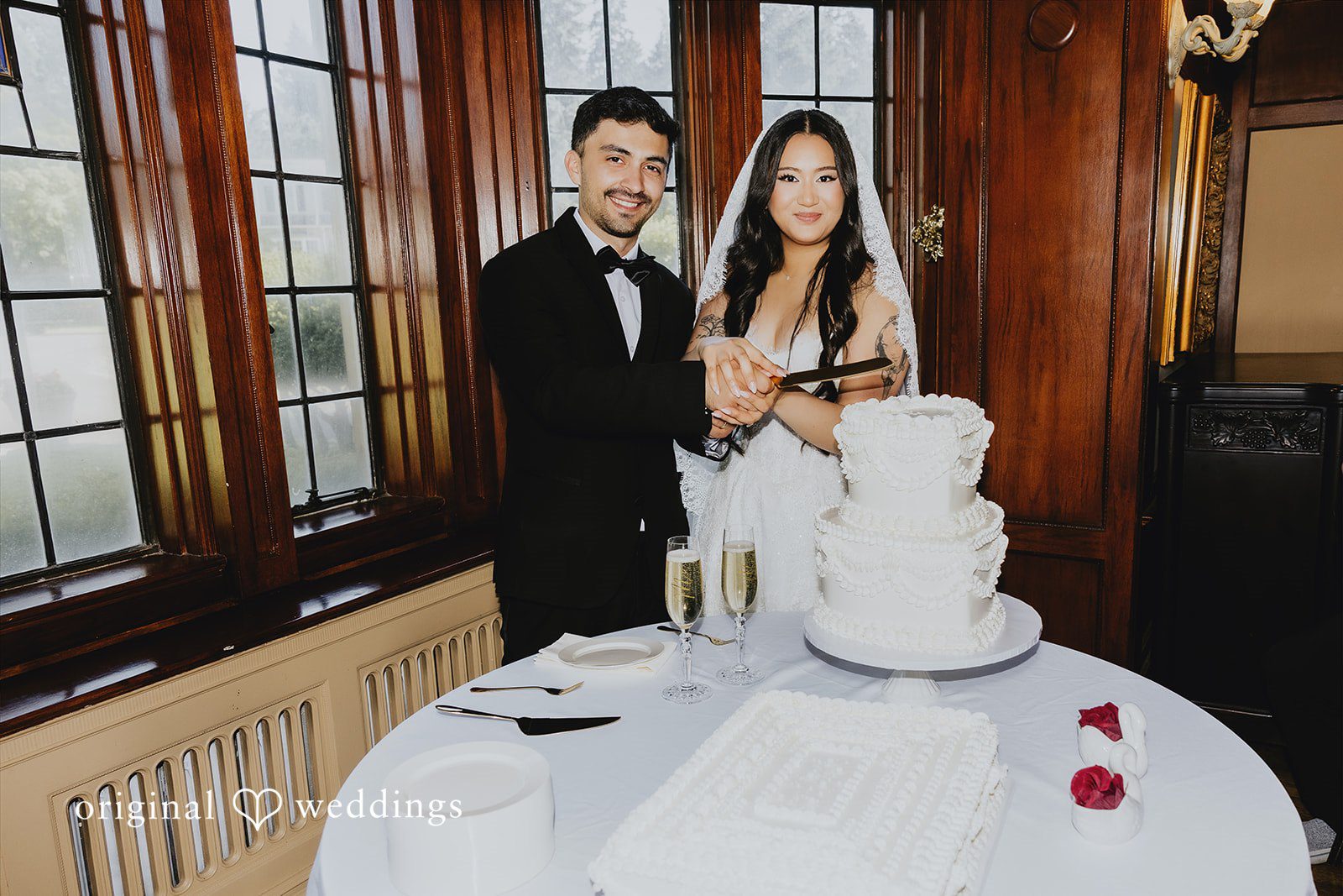 Sharmaine + Ronald A bride and groom smiling while standing behind a white wedding cake.