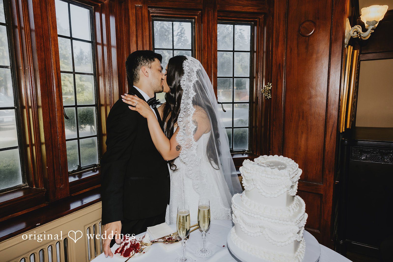 Sharmaine + Ronald A bride and groom sharing a close moment next to their multi-tiered wedding cake.