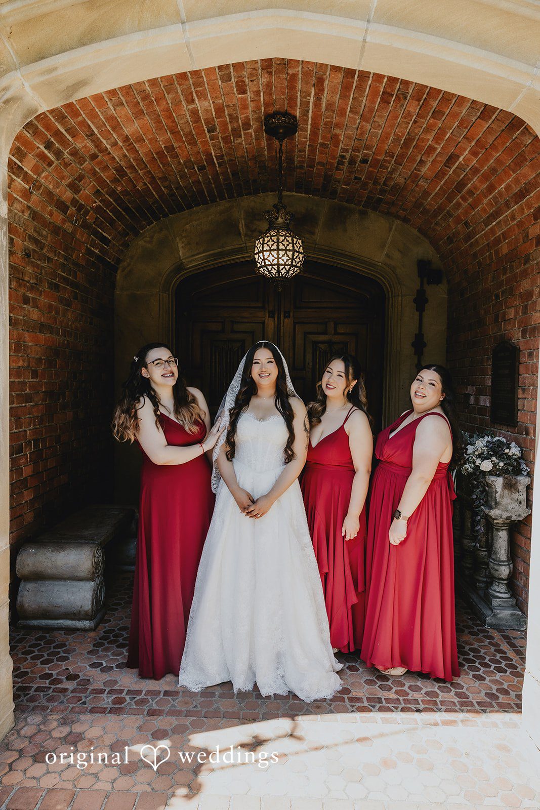 Sharmaine + Ronald A bride standing with her bridesmaids under a stone archway.