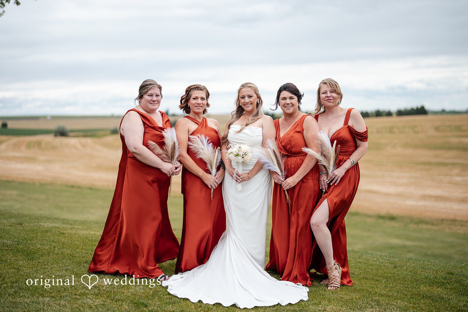 Kayla + Dillon A bride posing alongside her bridesmaids who are wearing vibrant red dresses.