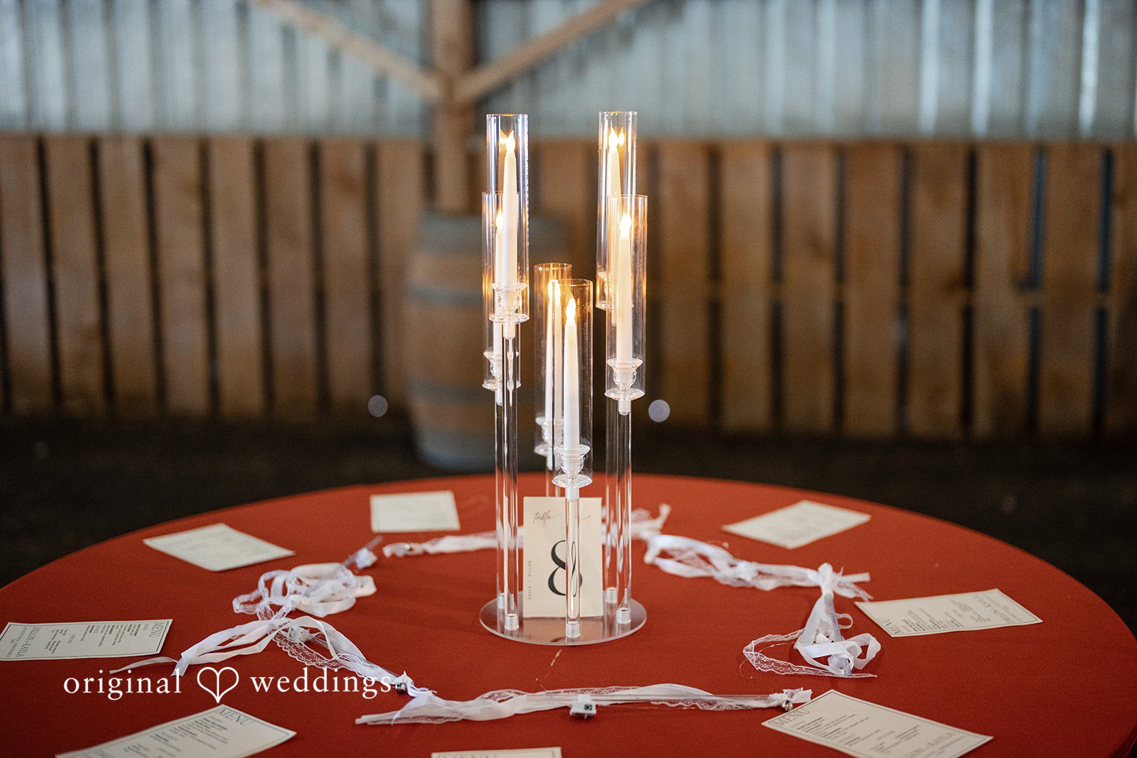 Kayla + Dillon A close-up of a circular table centerpiece featuring tall cylinder glass vases with floating candles.