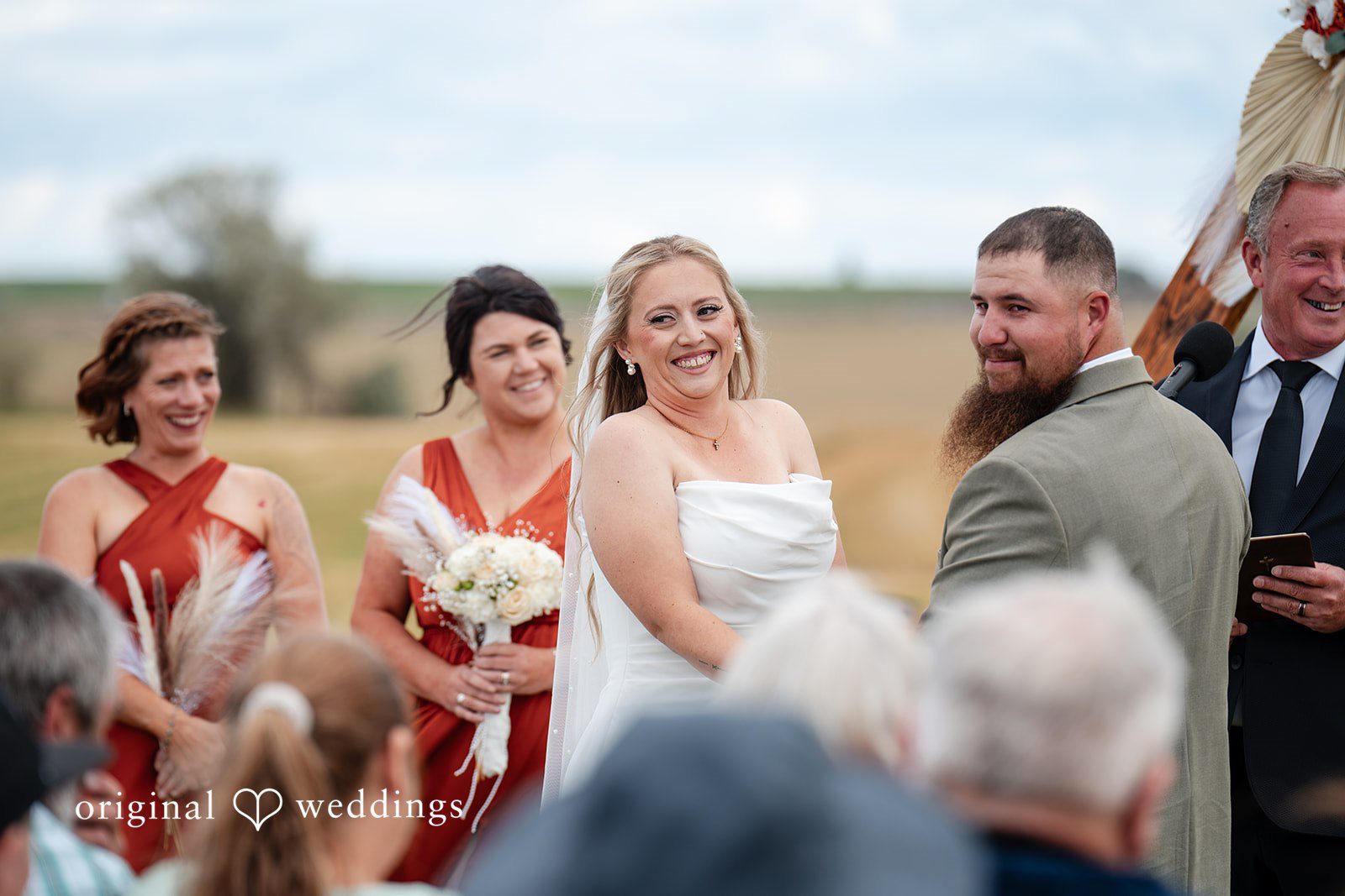Kayla + Dillon A bride smiling happily during the wedding ceremony surrounded by her bridal party.