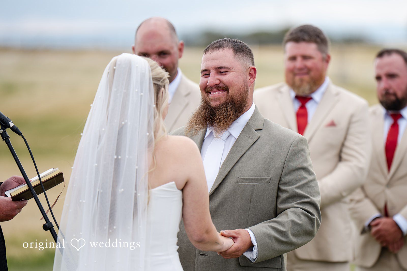 Kayla + Dillon A close-up of a bride looking lovingly at her groom as they hold hands at the altar.