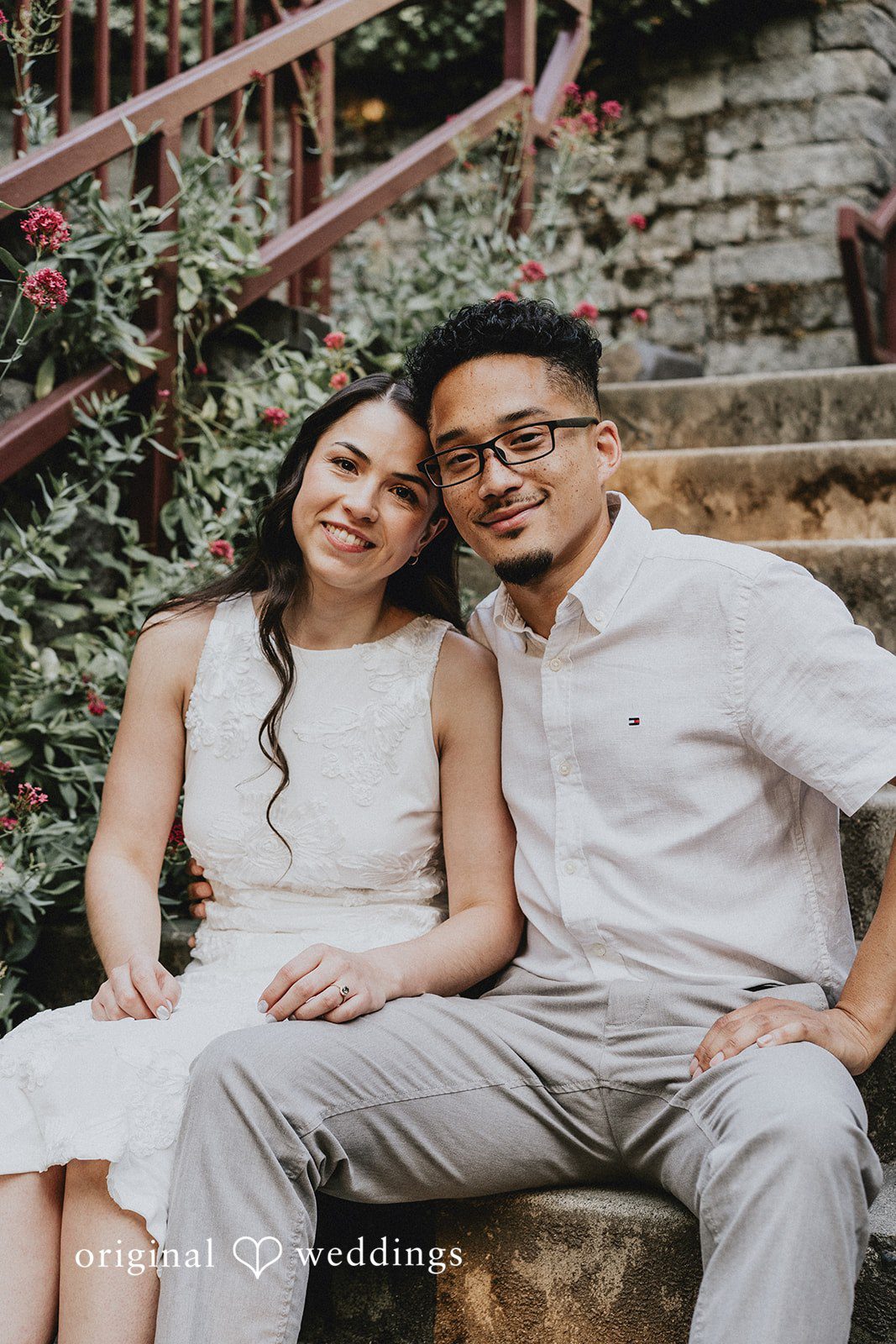 Couple smiling together while sitting on a rustic stone ledge.