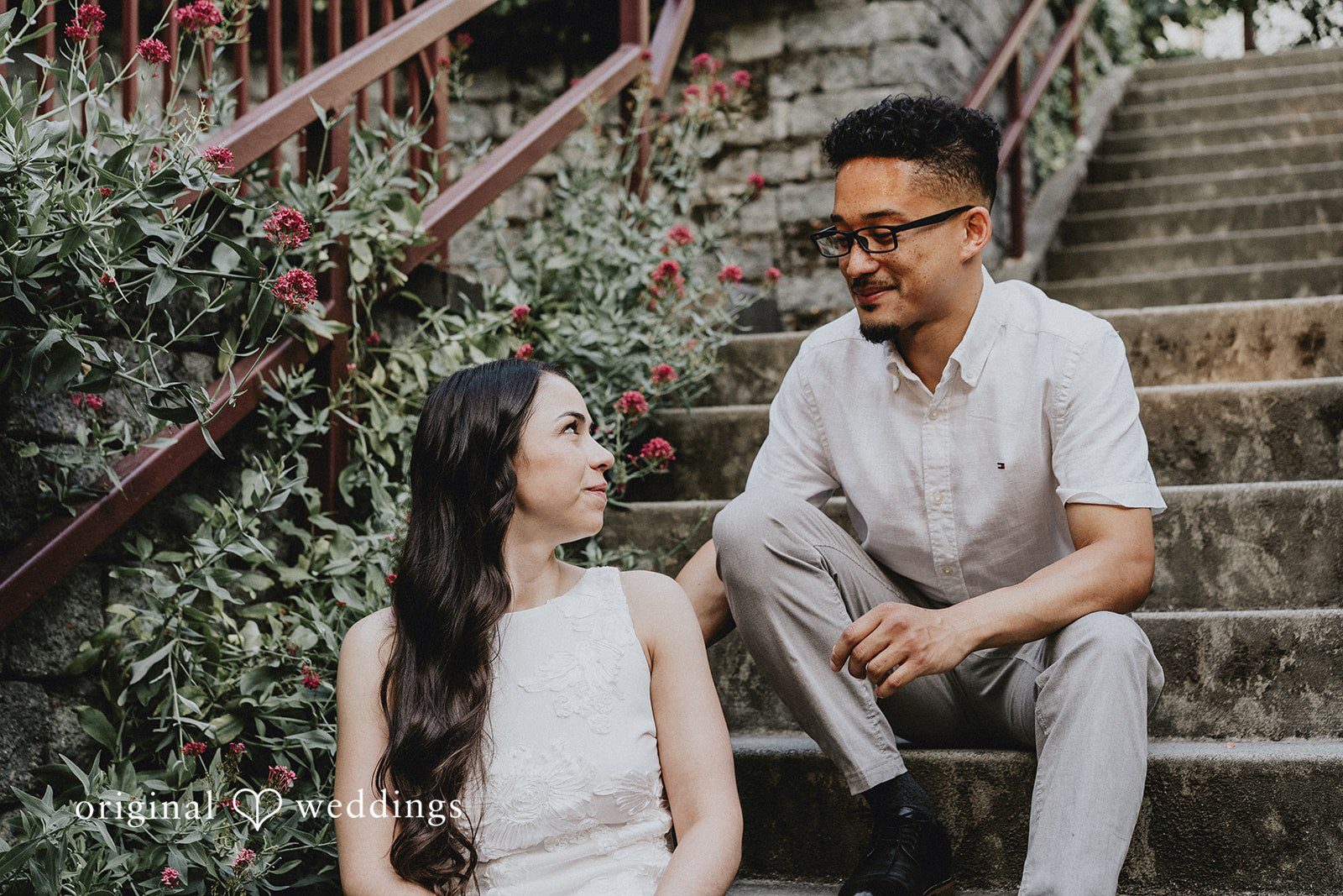 Couple sitting together on stone steps while looking off to the side.