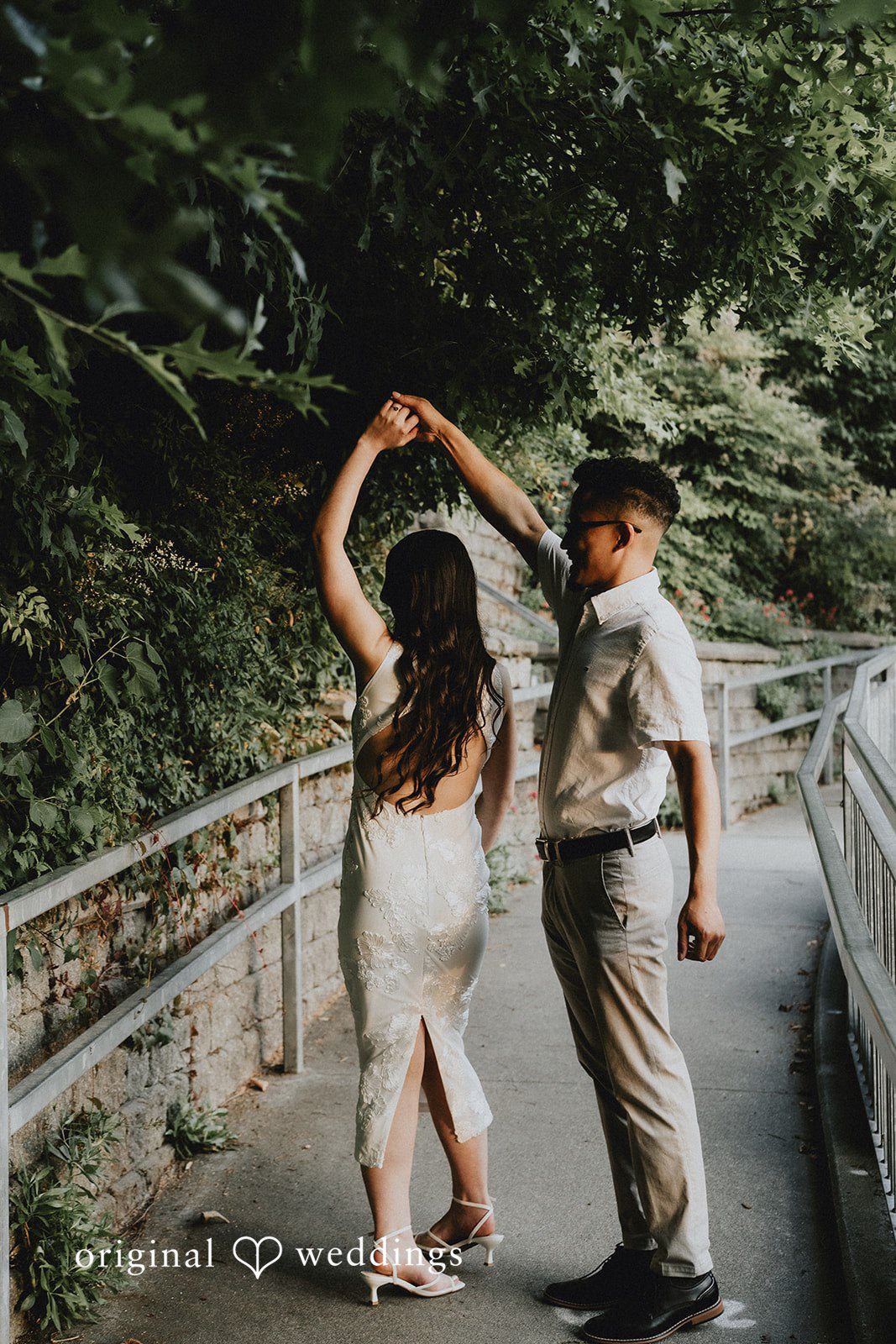 Couple dancing together on a paved pathway surrounded by trees.