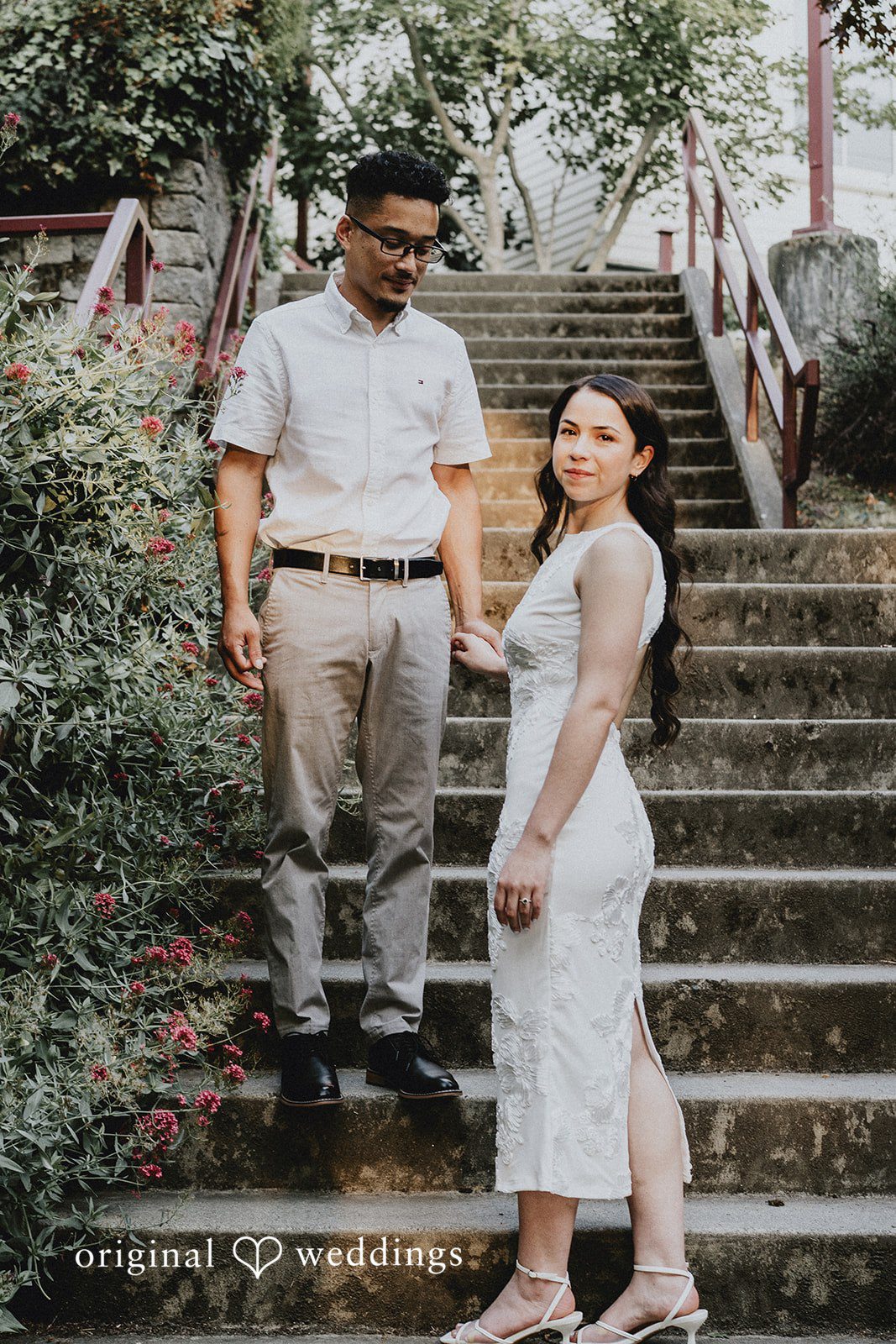 Couple posing together at the bottom of a wide stone staircase.