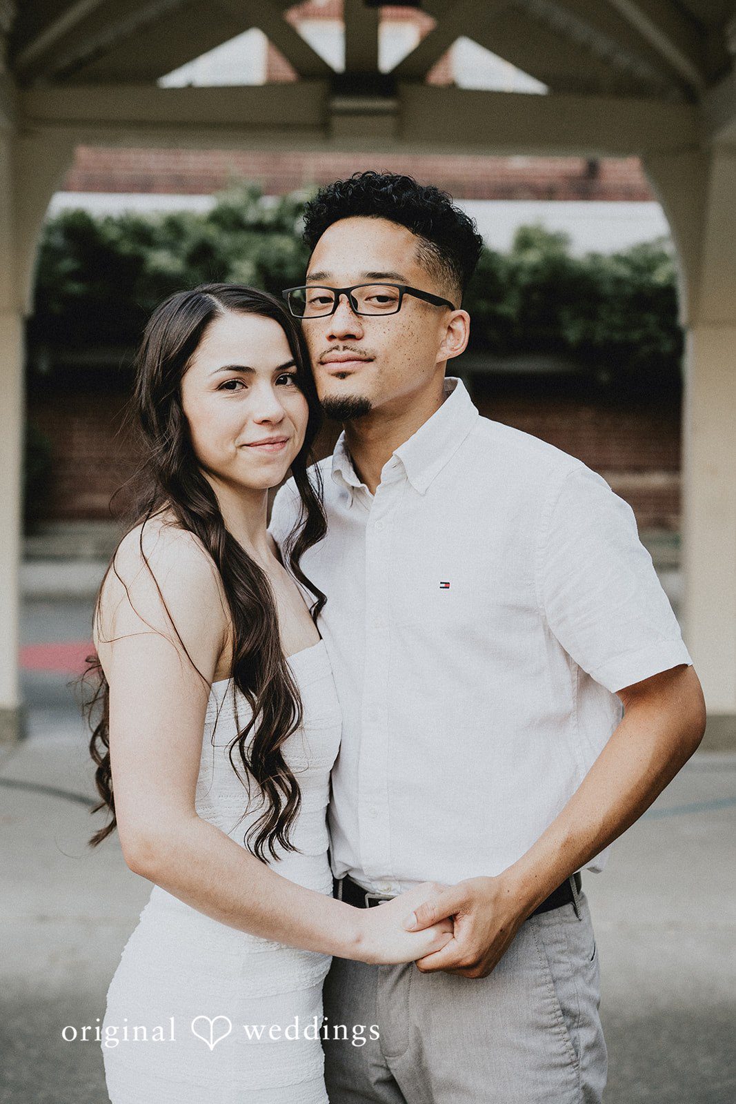 Couple posing closely together with the man holding the woman's hand.