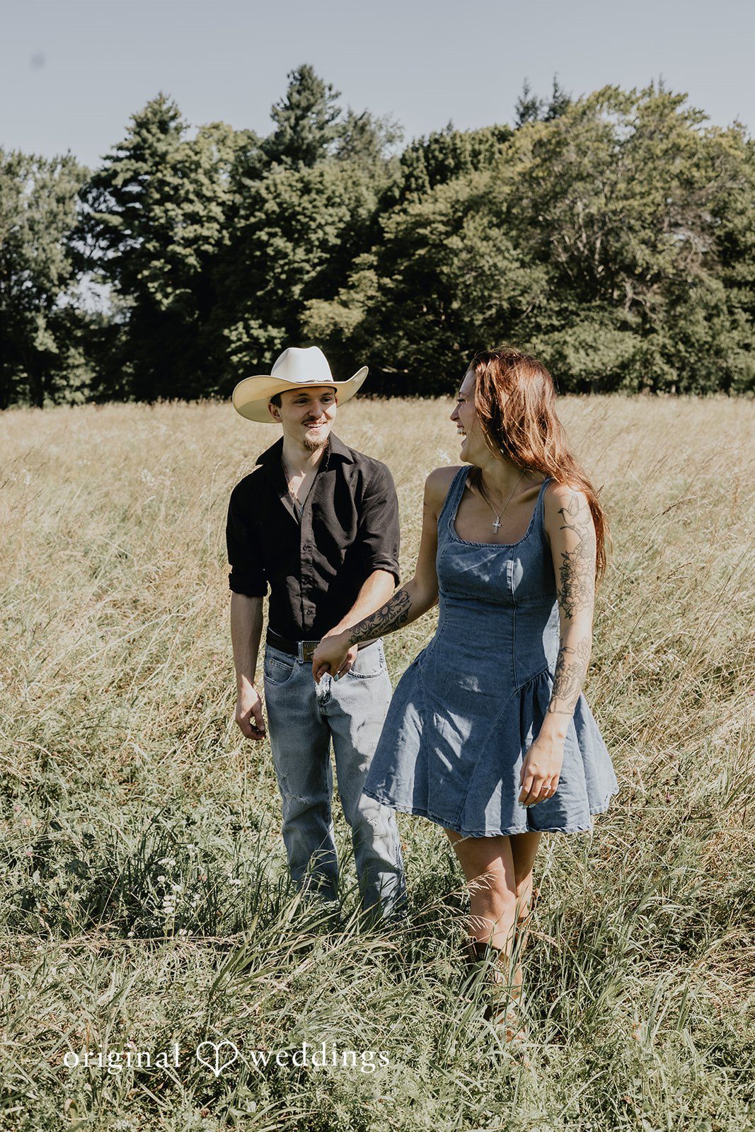 Meghan + Kal Couple walk hand-in-hand through an open grassy field.