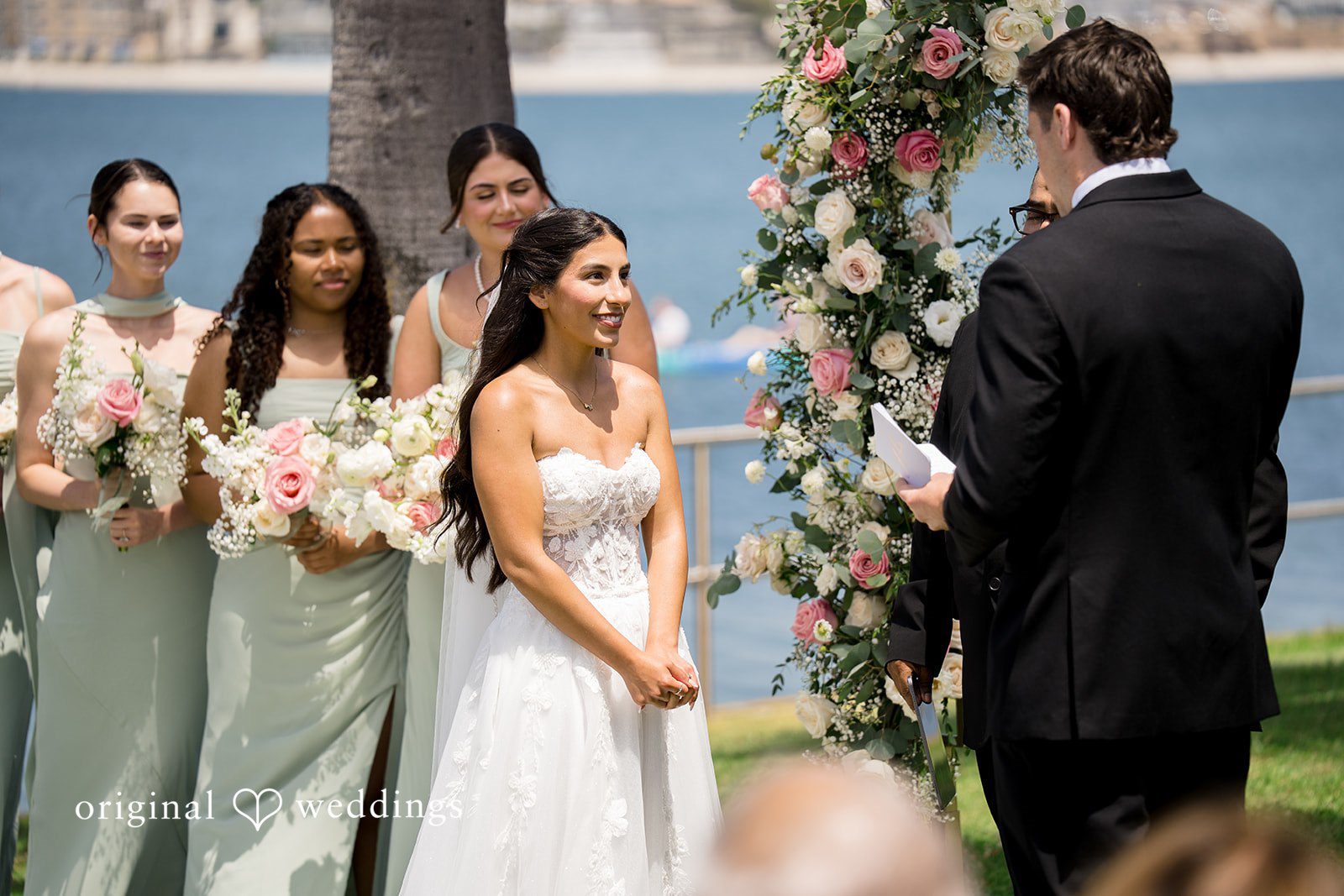 Kalina + Malakai A bride and groom standing before the officiant with bridesmaids at their side.
