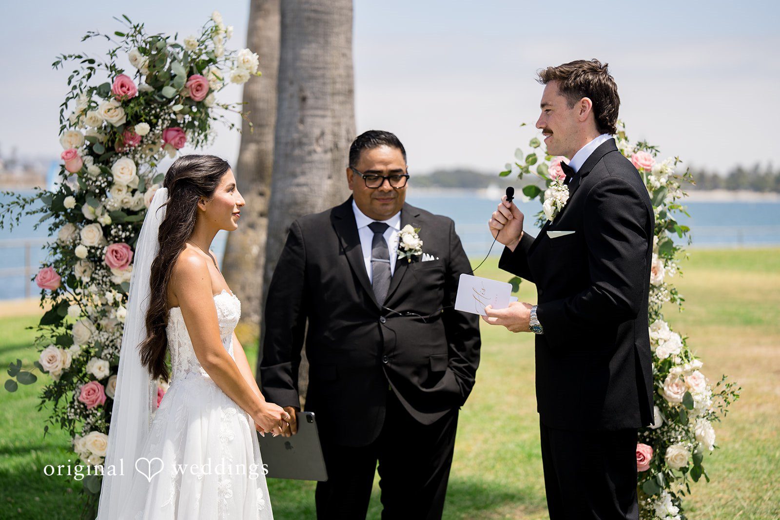 Kalina + Malakai A bride and groom looking each other during their wedding ceremony near a floral arch.
