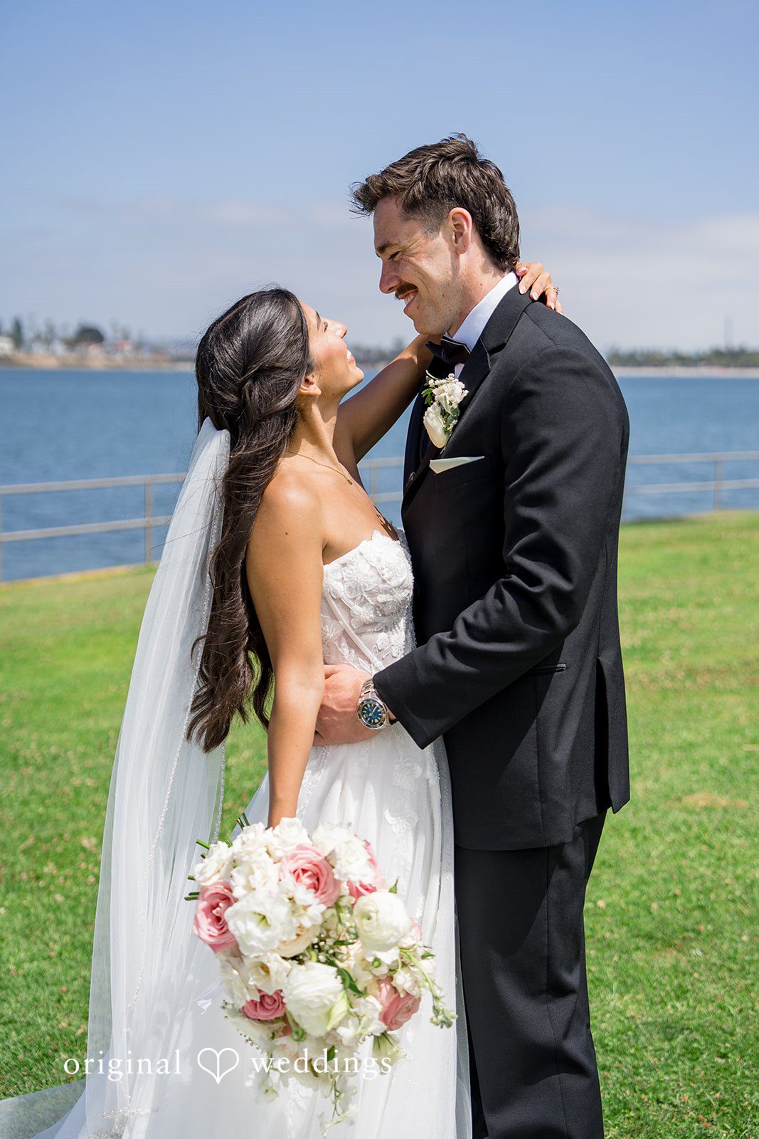 Kalina + Malakai Groom holding the bride from behind while she smiles and holds a bouquet.