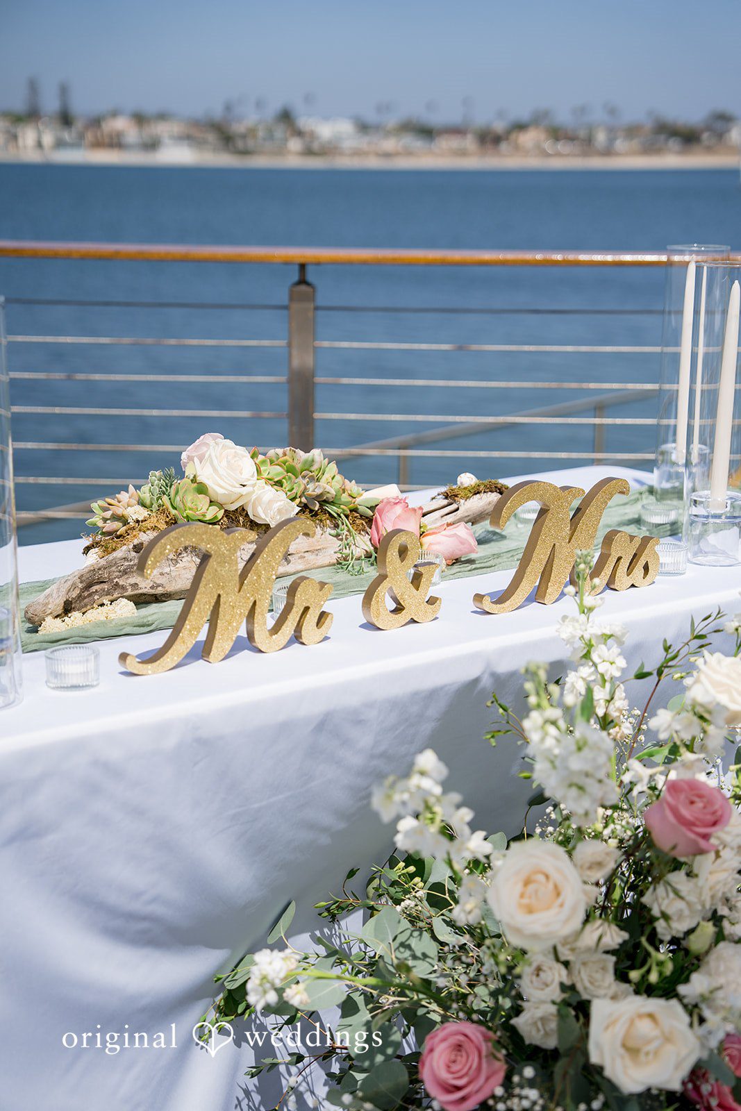 Kalina + Malakai A food table decorated with lush green garlands and white floral arrangements.