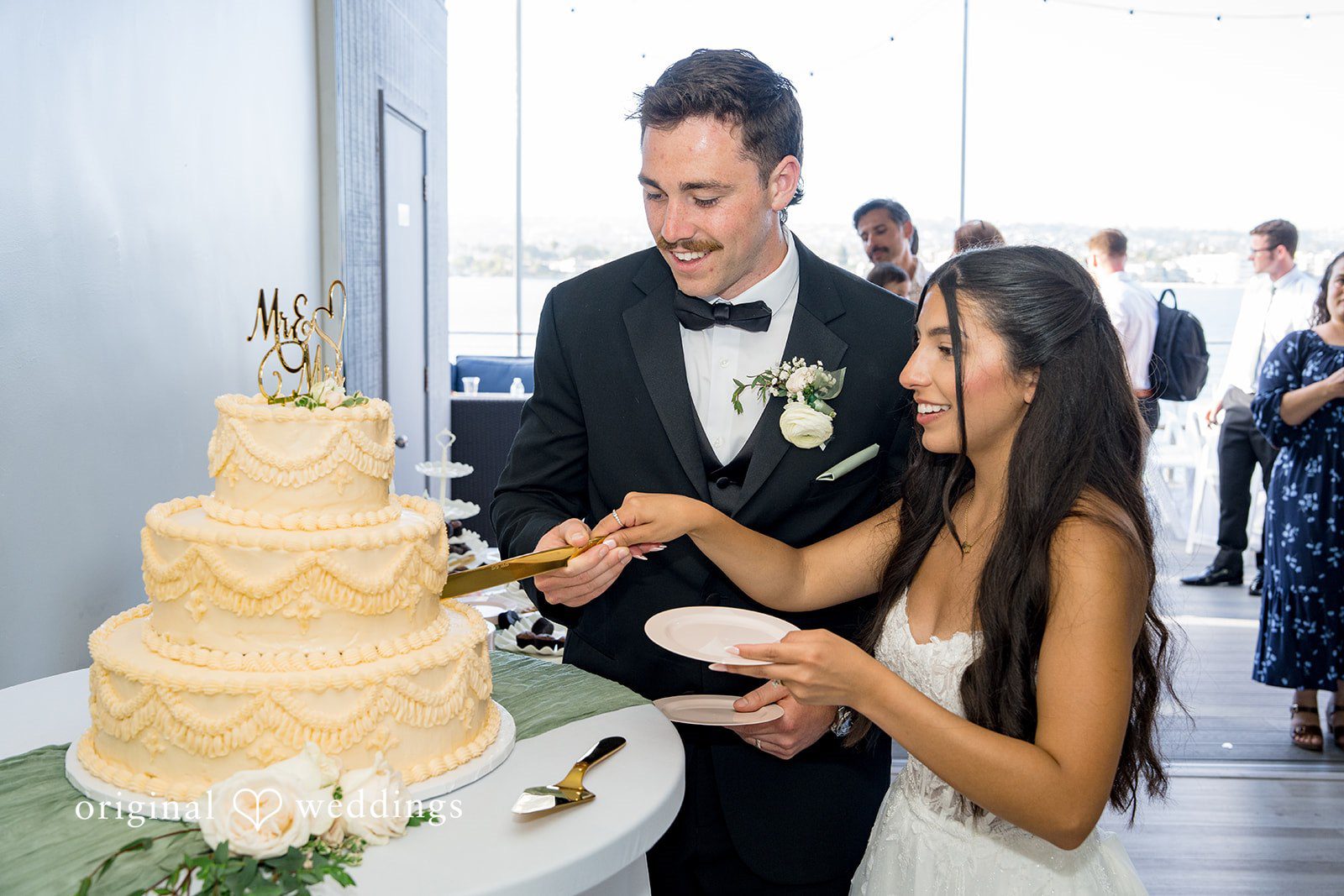 Kalina + Malakai Bride and groom cutting their multi-tiered white wedding cake.