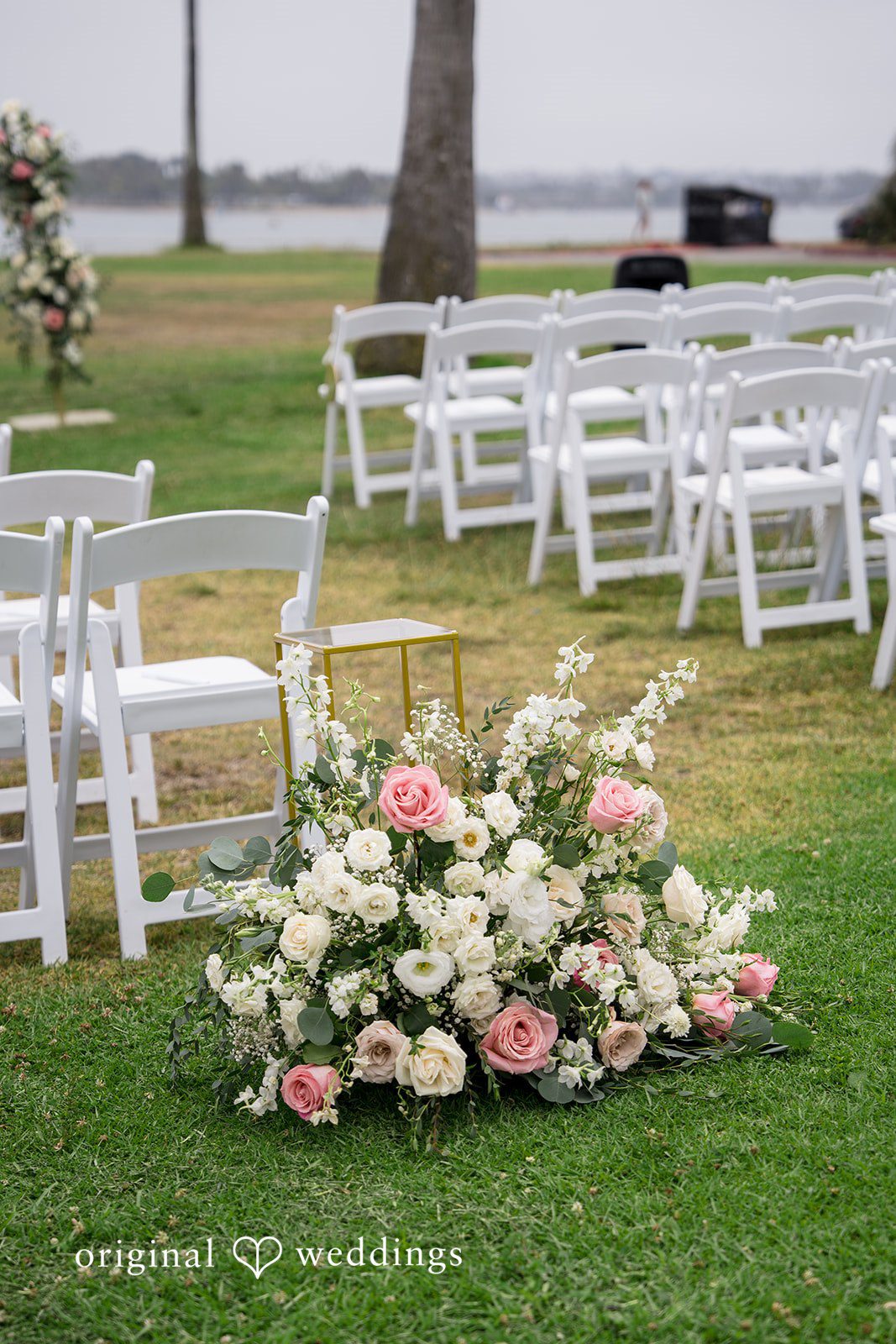 Kalina + Malakai A large floral arrangement of pink and white roses placed on a grassy field.