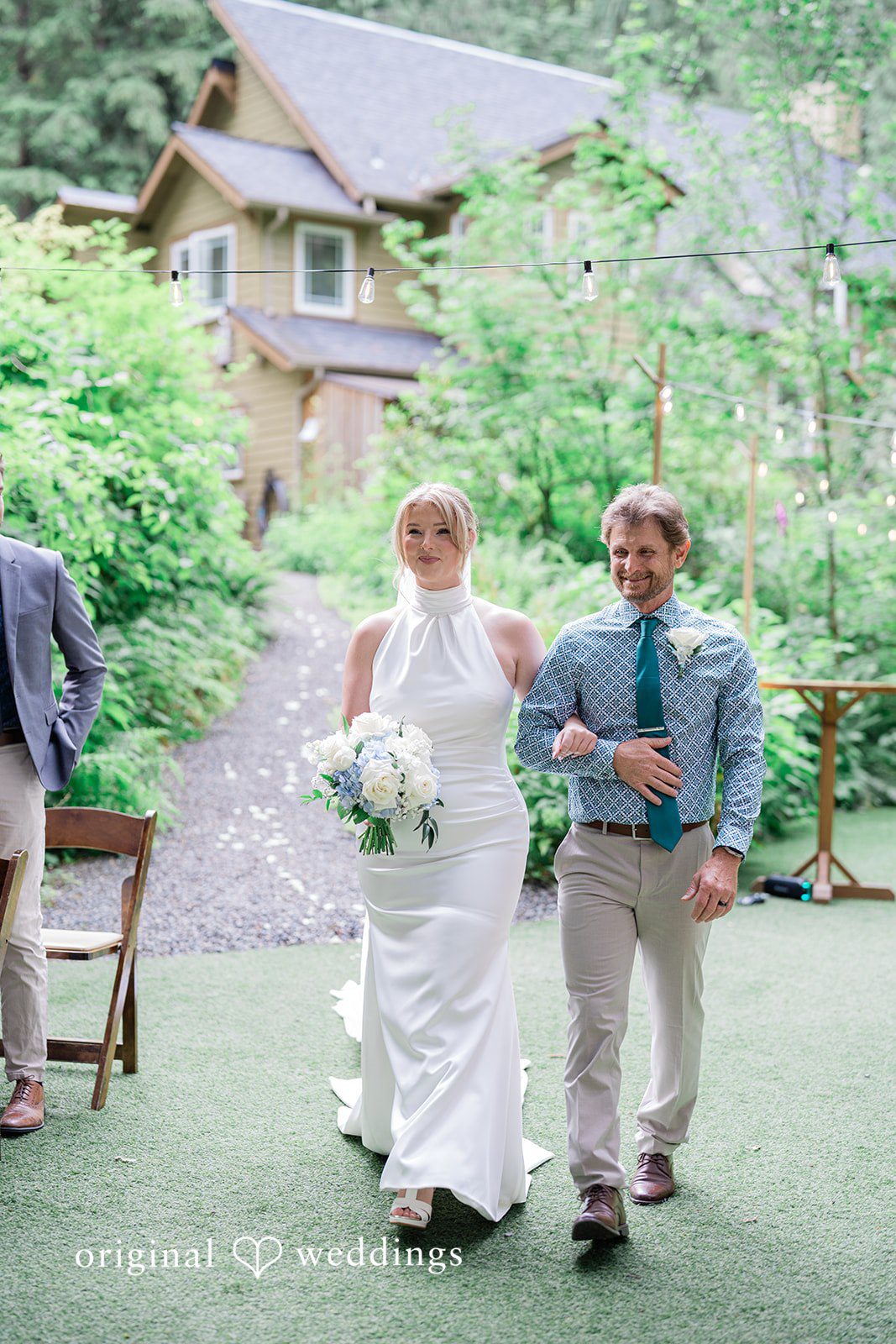 Destiny + Maksim A bride walking down a paved garden path accompanied by men.
