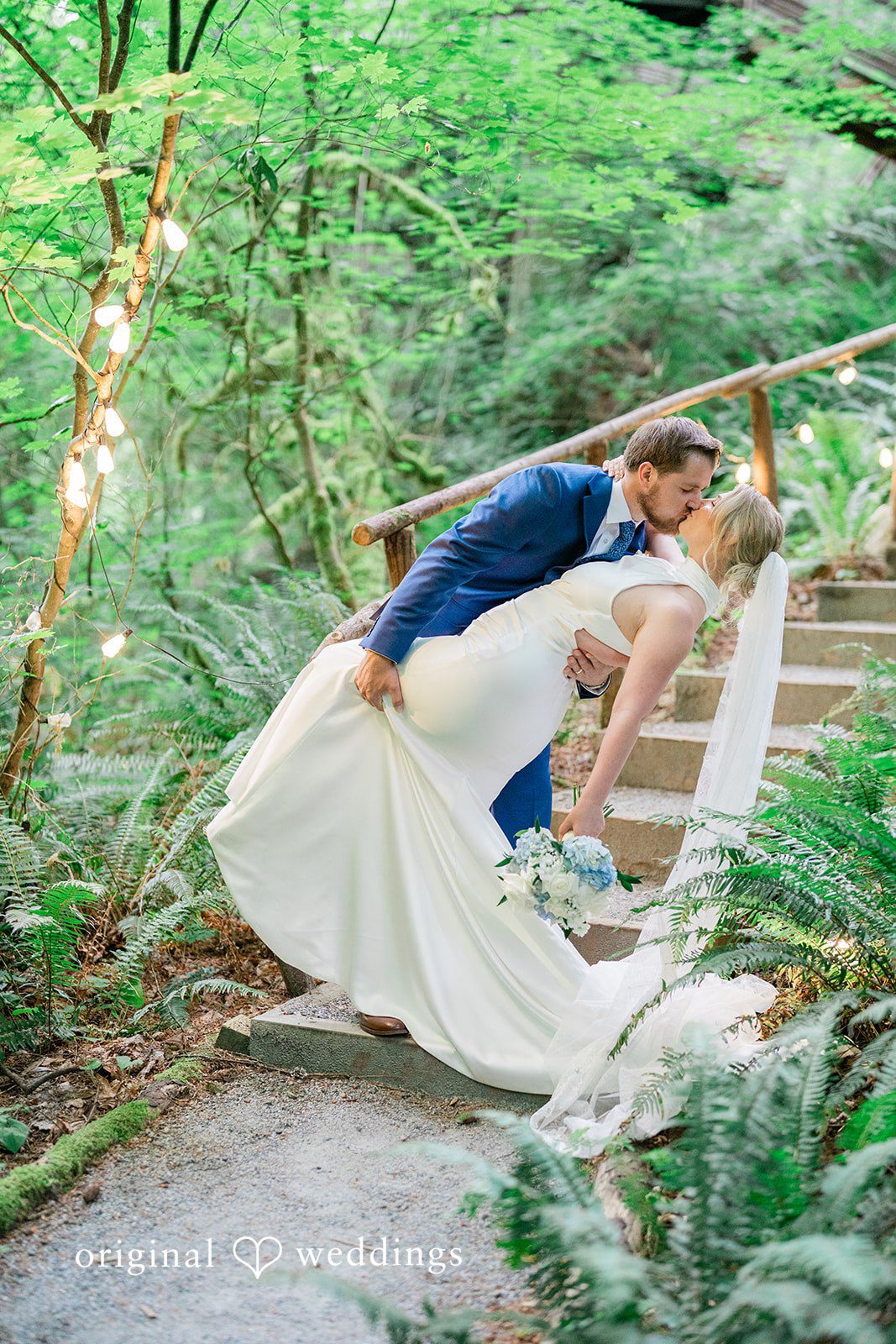 Destiny + Maksim A groom dipping his bride while sharing a kiss on a stone staircase.