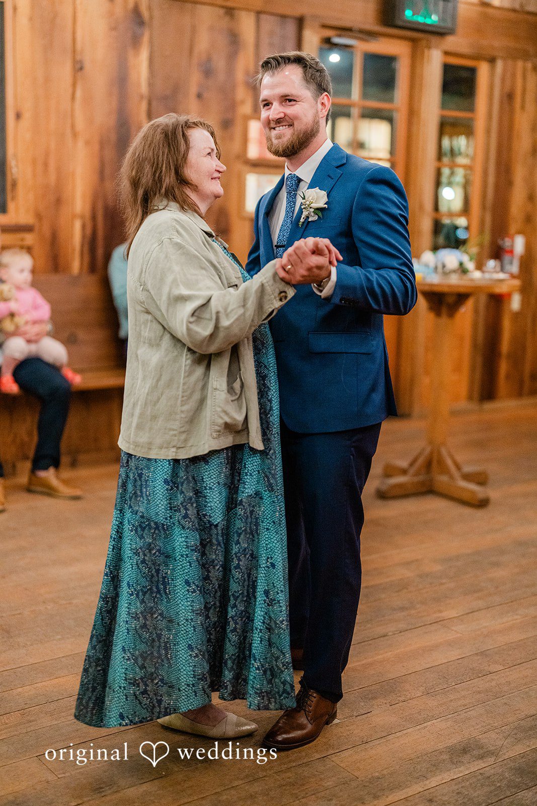 Destiny + Maksim A groom smiling while dancing with a woman in a floral jacket.