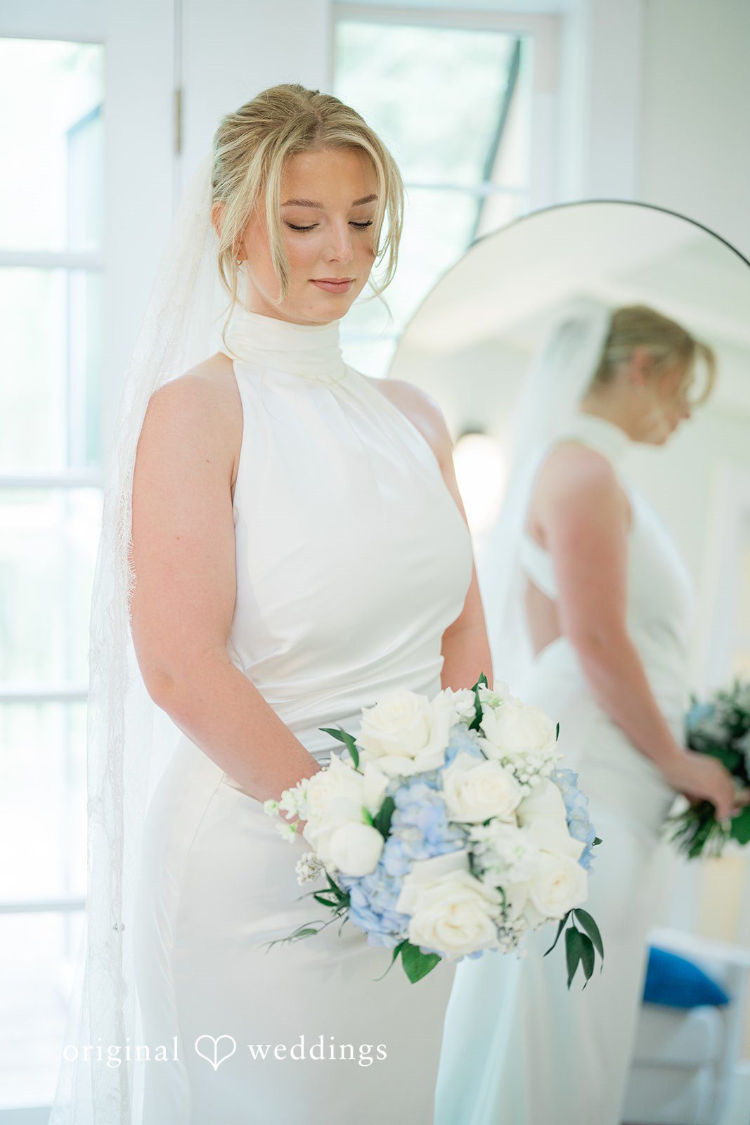 Destiny + Maksim A close-up of a smiling bride holding a bouquet of white and blue flowers.