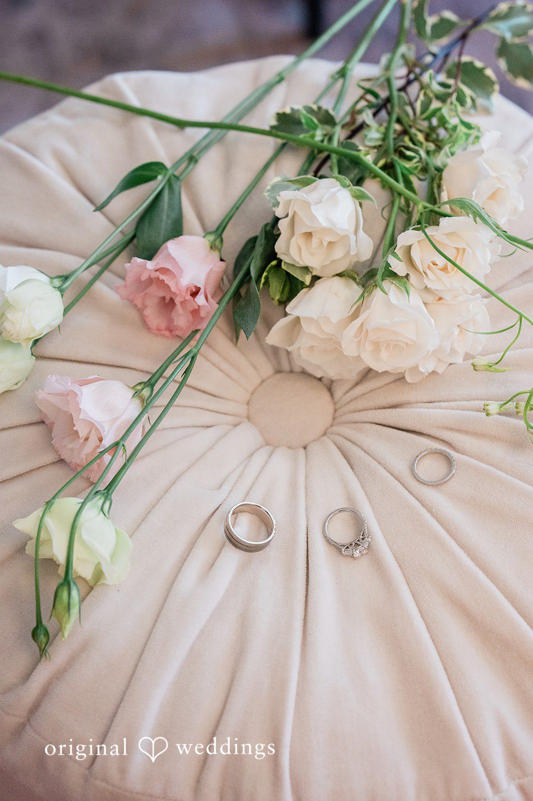 Luke + Kelsey A close-up shot of two wedding rings resting on top of a bridal bouquet.