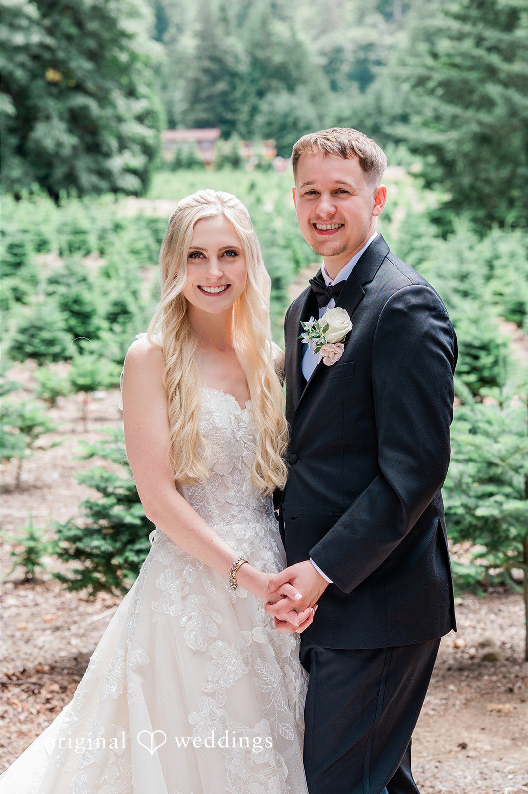 Luke + Kelsey A bride and groom smiling together in a field of trees.