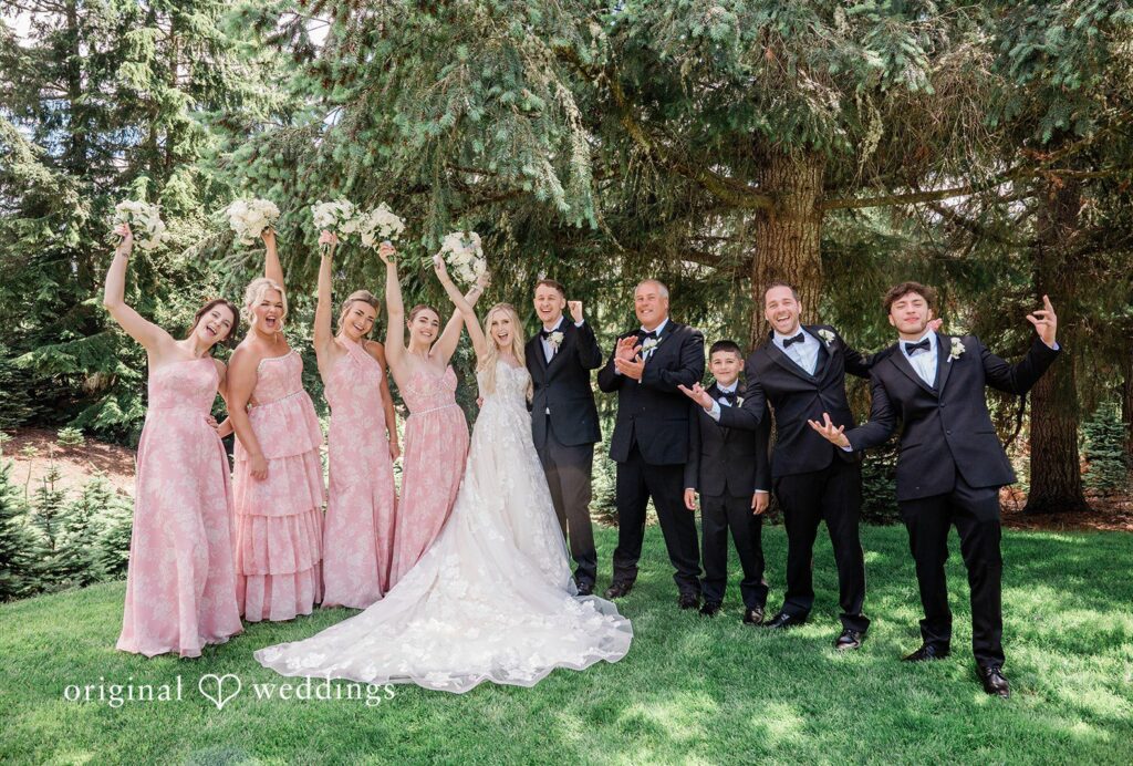 Luke + Kelsey A wedding party posing together on a lawn lined with trees captured by Seattle wedding photographers from Original Weddings at Trinity Tree Farm