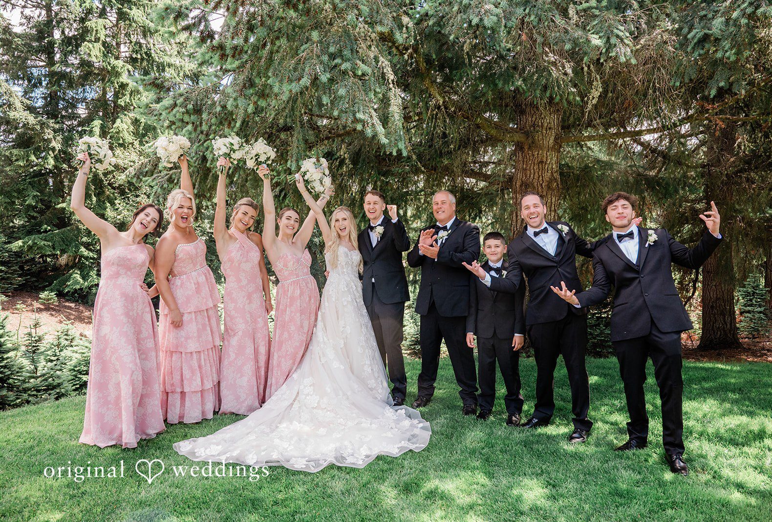 A wedding party posing together on a lawn lined with trees captured by Seattle wedding photographers from Original Weddings at Trinity Tree Farm