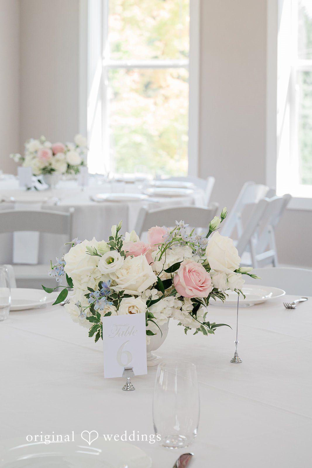 Luke + Kelsey A formal reception table centerpiece featuring white and light pink roses.