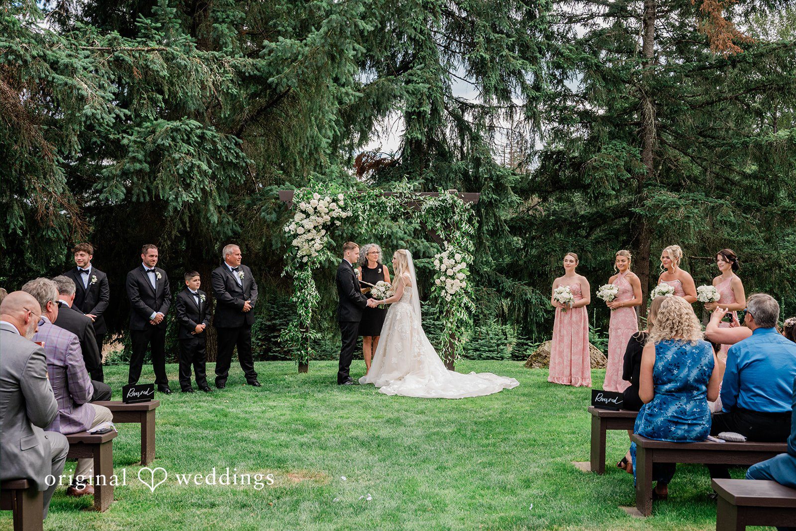 Luke + Kelsey A wide shot of a wedding ceremony with guests seated in rows.