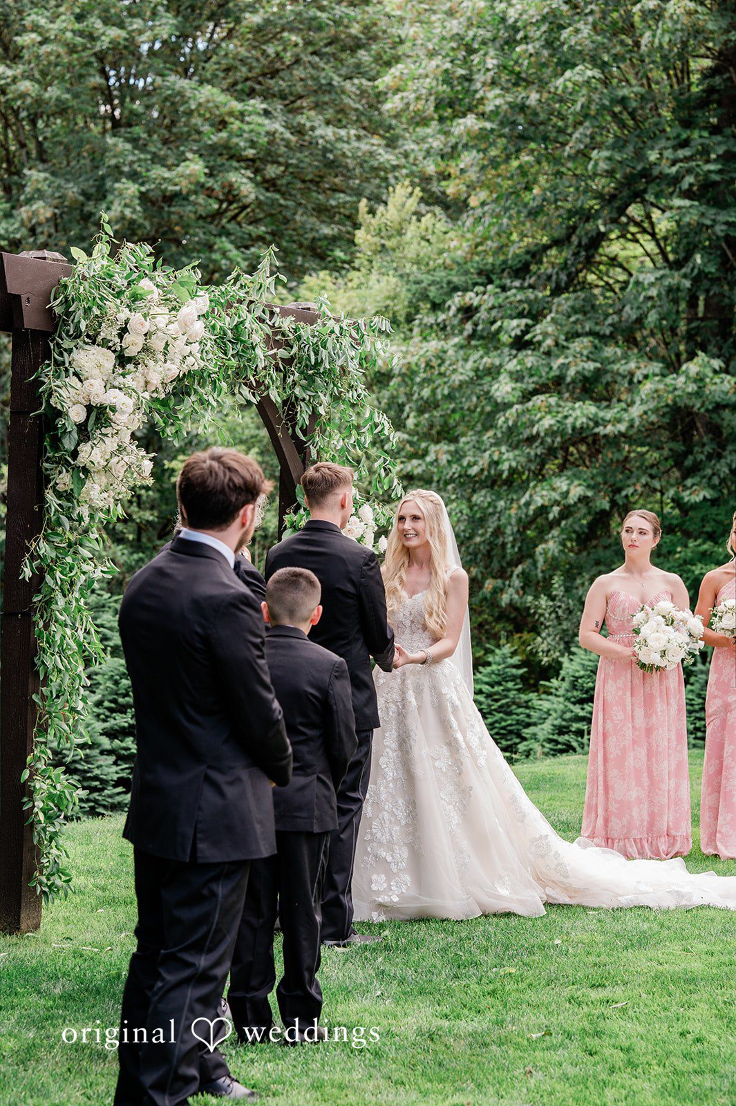Luke + Kelsey A bride and groom standing together on a lawn surrounded by guests.