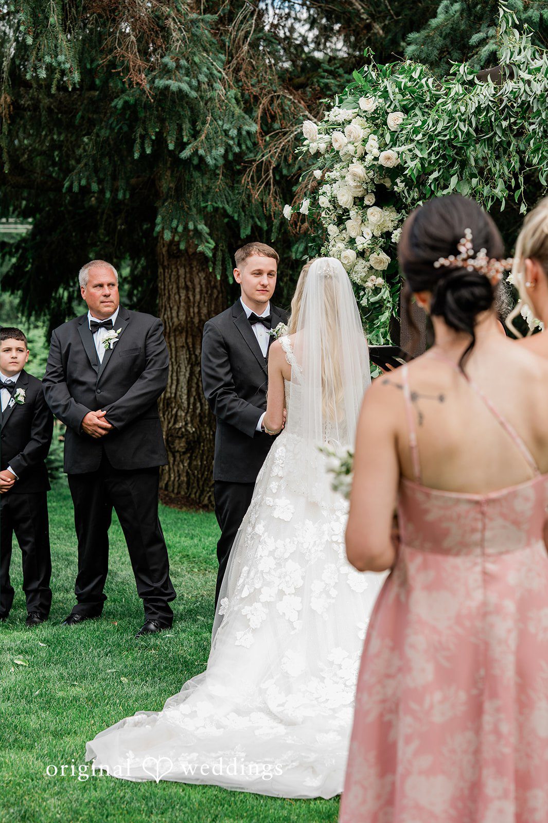 Luke + Kelsey A wedding celebration with a bride in a white dress and guests nearby.