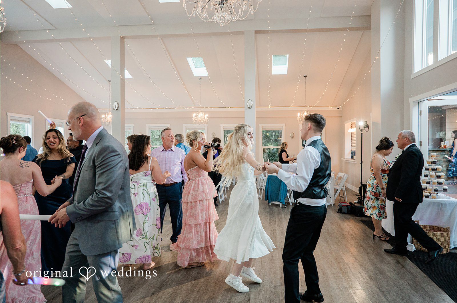 Luke + Kelsey Wedding guests dancing together in a bright reception hall.
