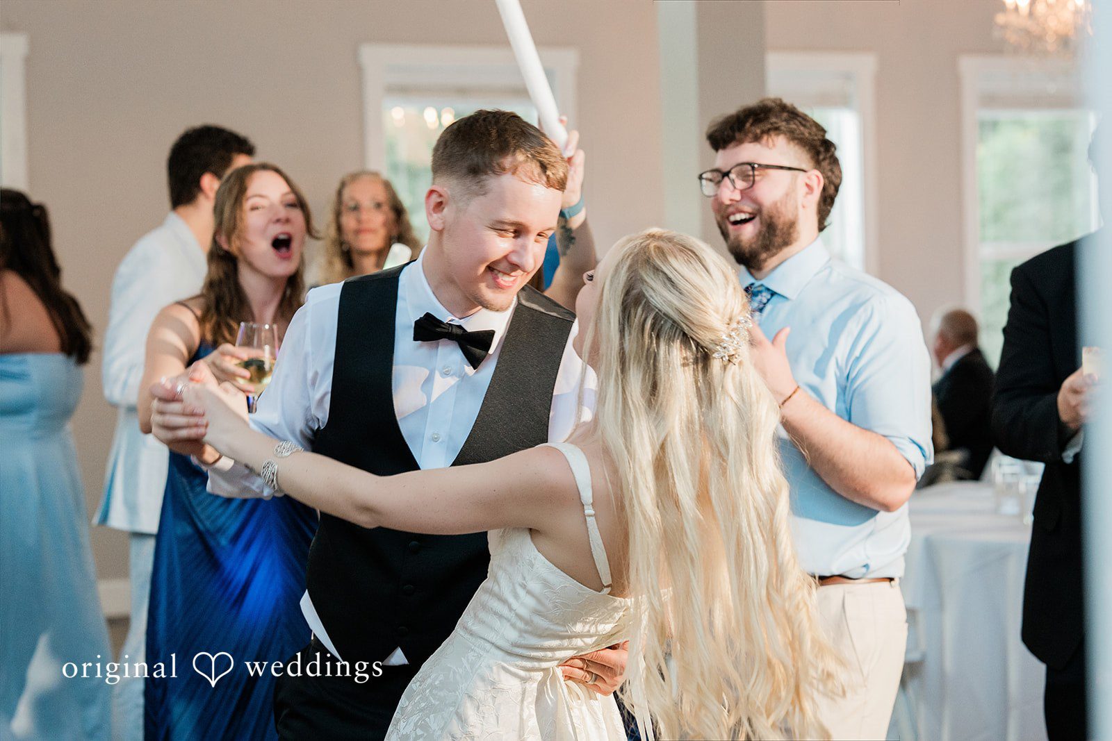 Luke + Kelsey A bride and groom sharing a laugh while dancing with friends.
