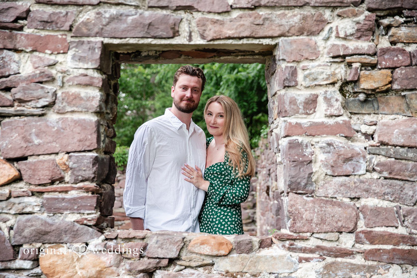 Sarah + Tyler A smiling couple poses together inside the stone window frame of a rustic ruin.