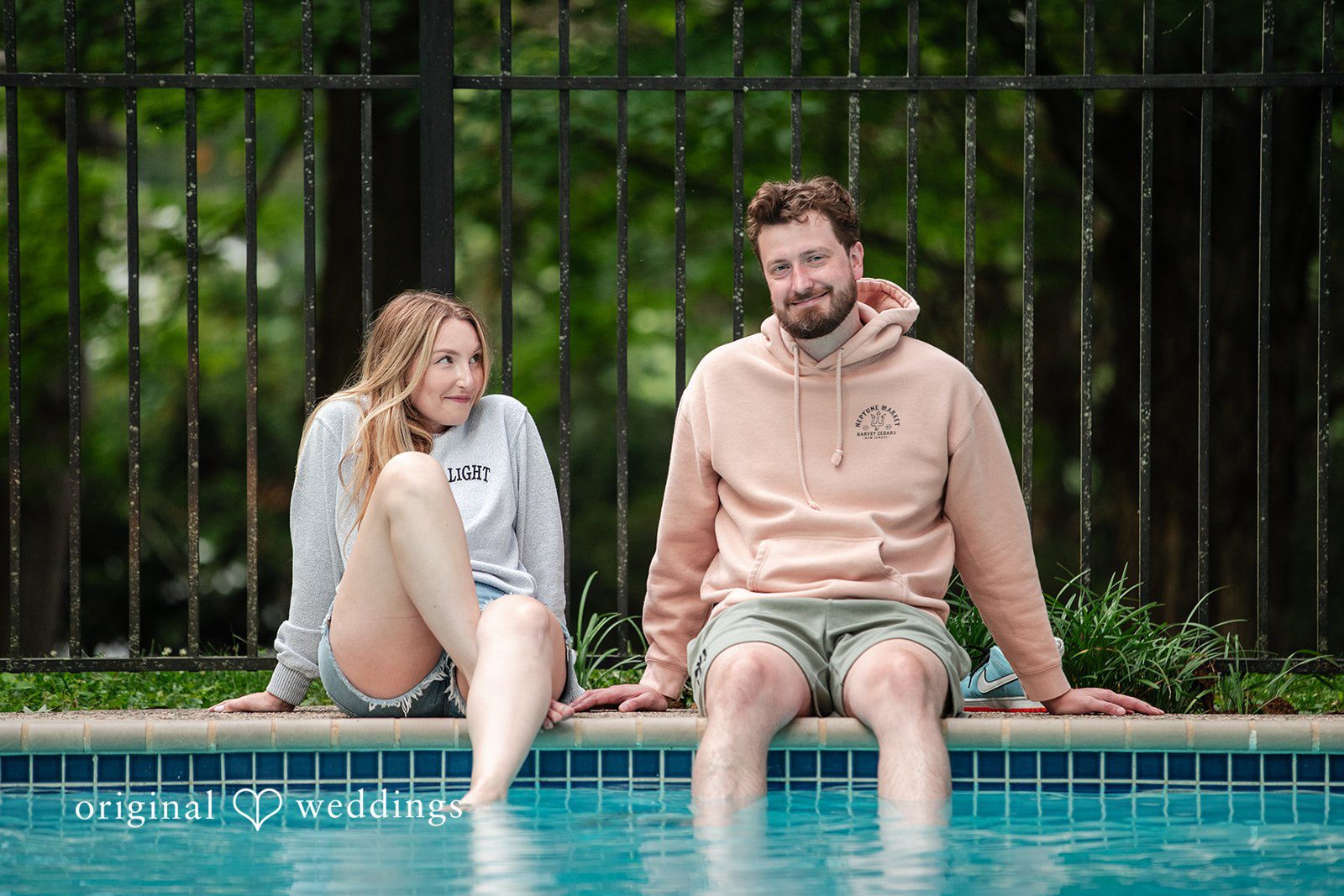 Sarah + Tyler A couple sits side-by-side on the edge of a swimming pool.