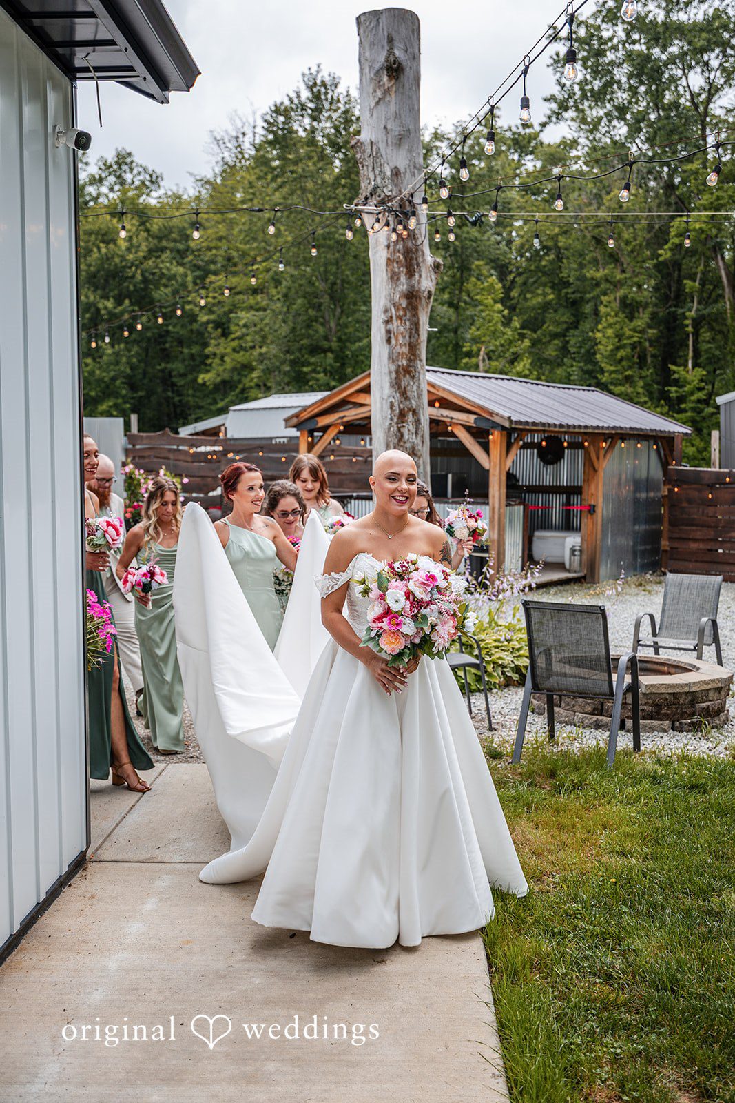 Savannah + Phillip A bride walking across a grassy lawn with her long white dress train trailing behind her.