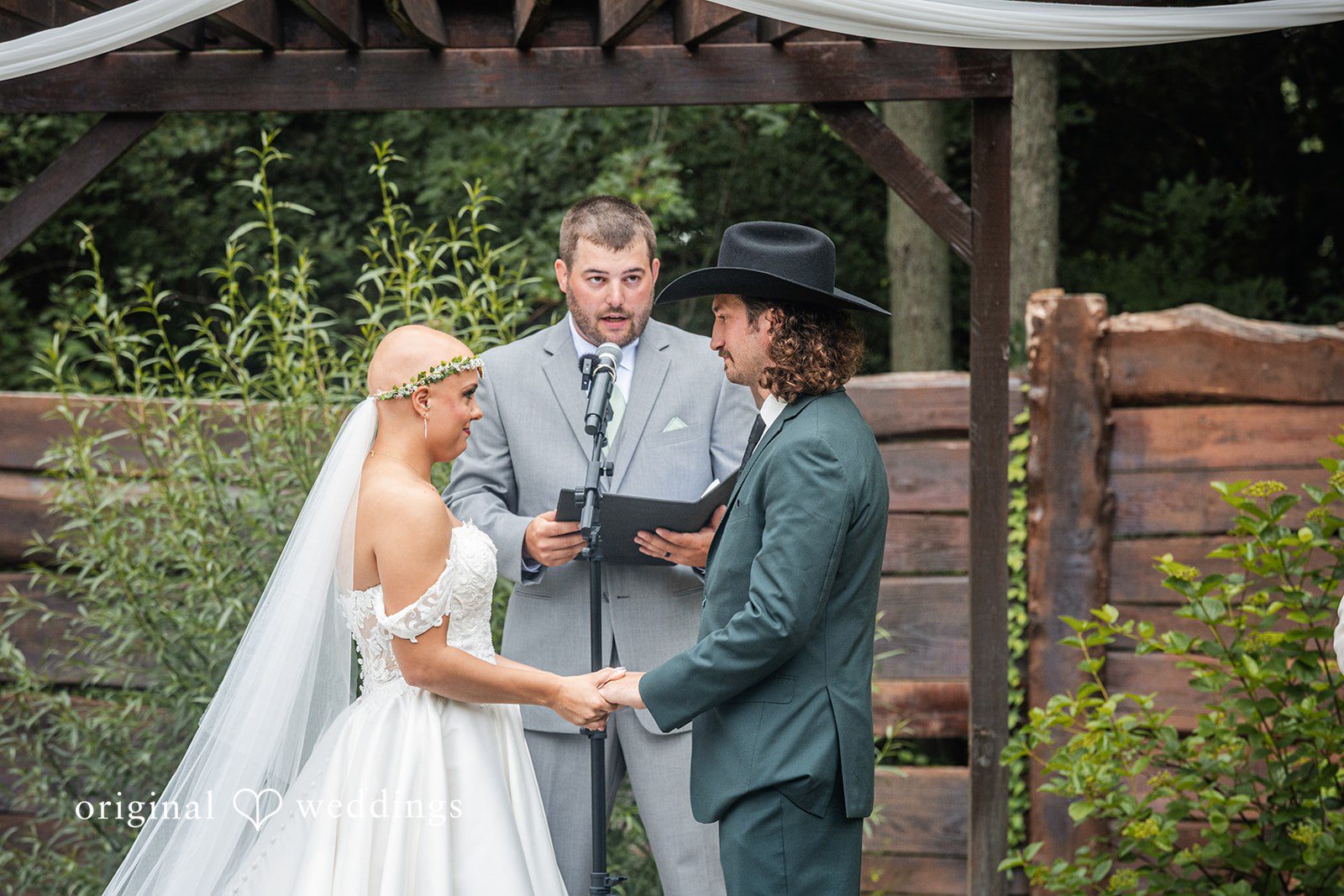 Savannah + Phillip A close-up view of a bride and groom during their wedding ceremony under an arbor.