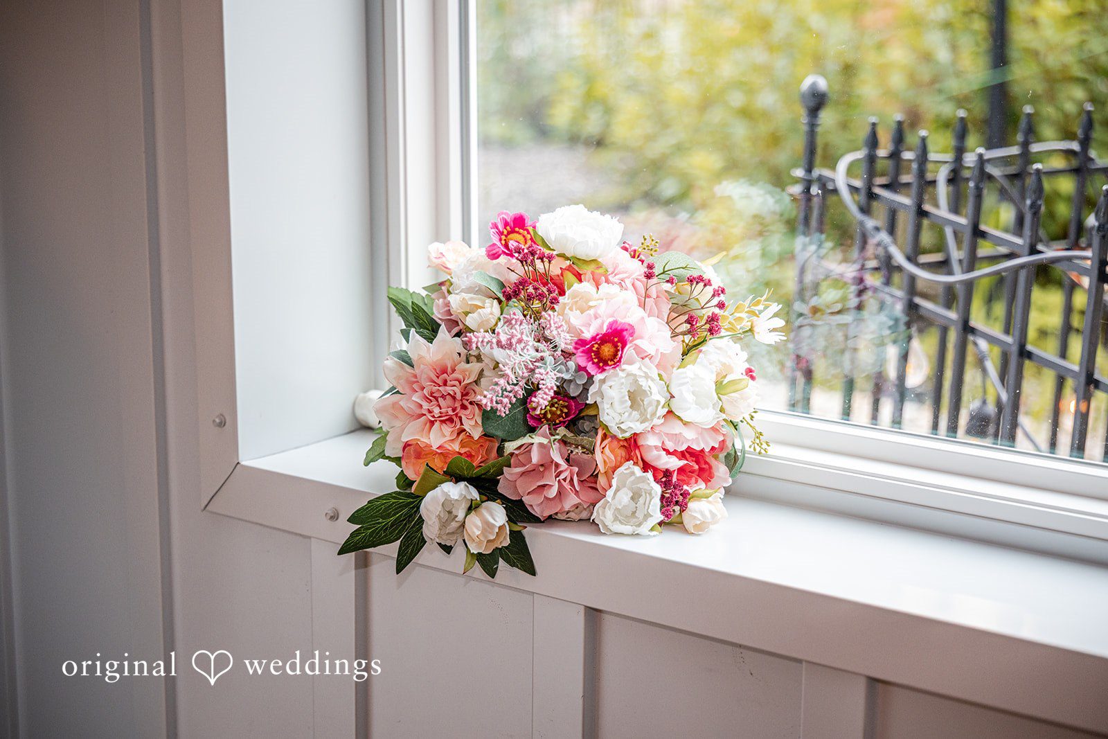 Savannah + Phillip A vibrant wedding bouquet with pink, white, and red flowers sitting on a ledge.