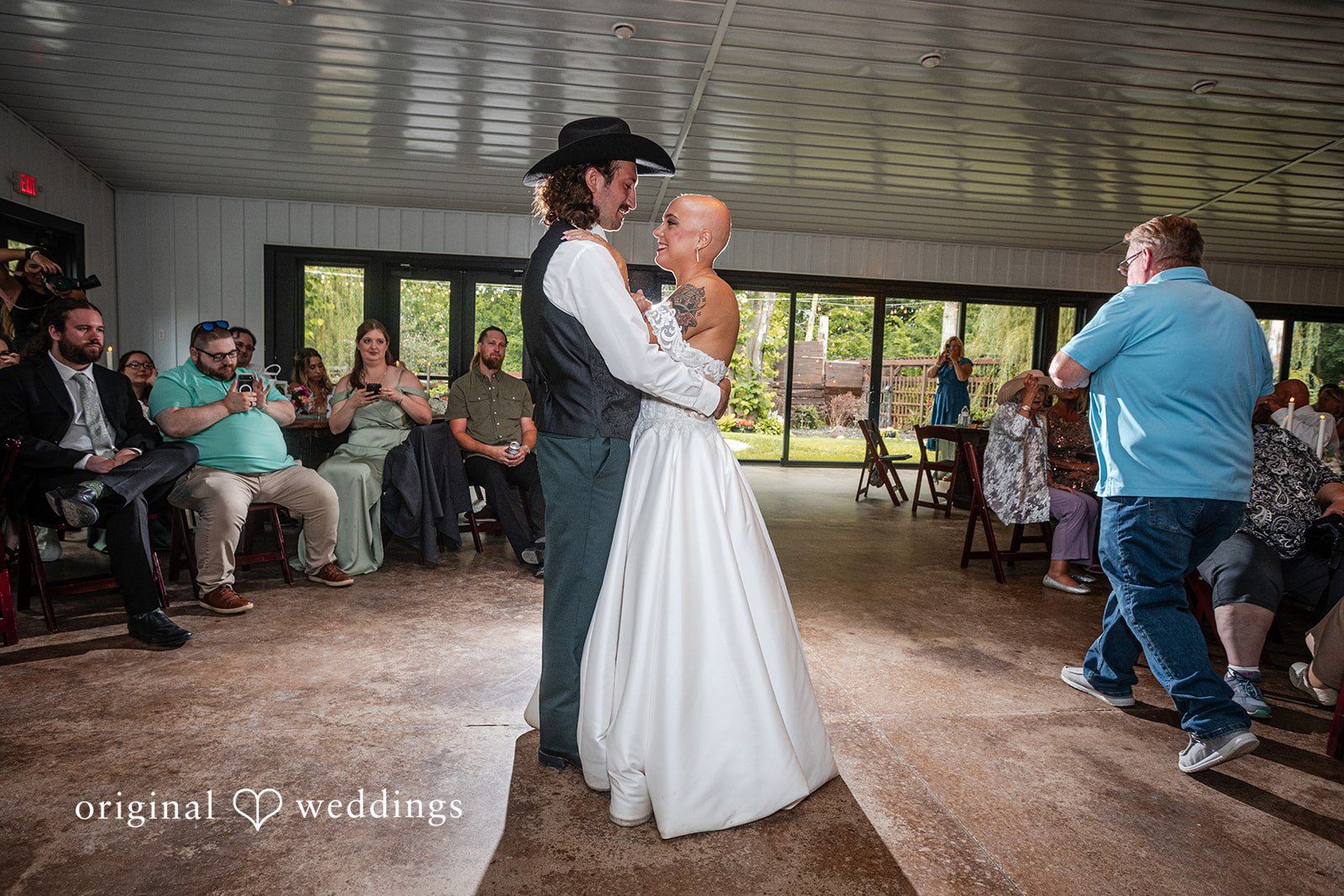 Savannah + Phillip A bride and groom sharing their first dance on a wooden floor inside a reception venue filled with guests.