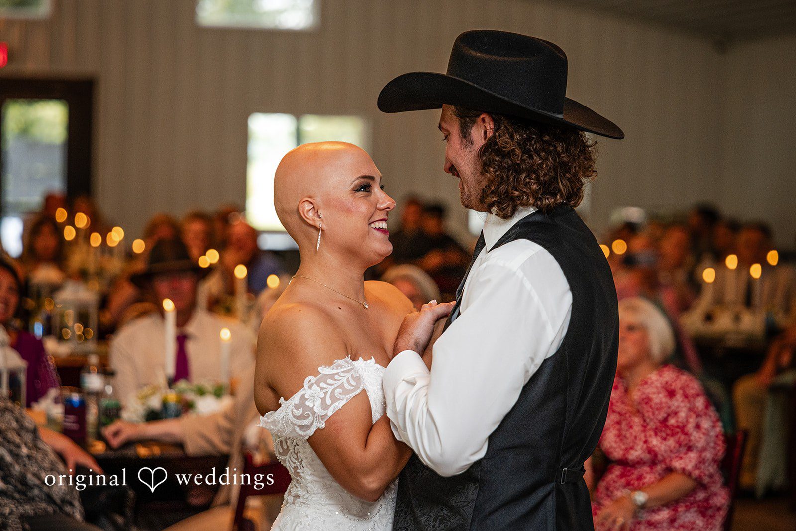 Savannah + Phillip A bride and groom dancing together closely at their reception with warm candle lighting in the background.