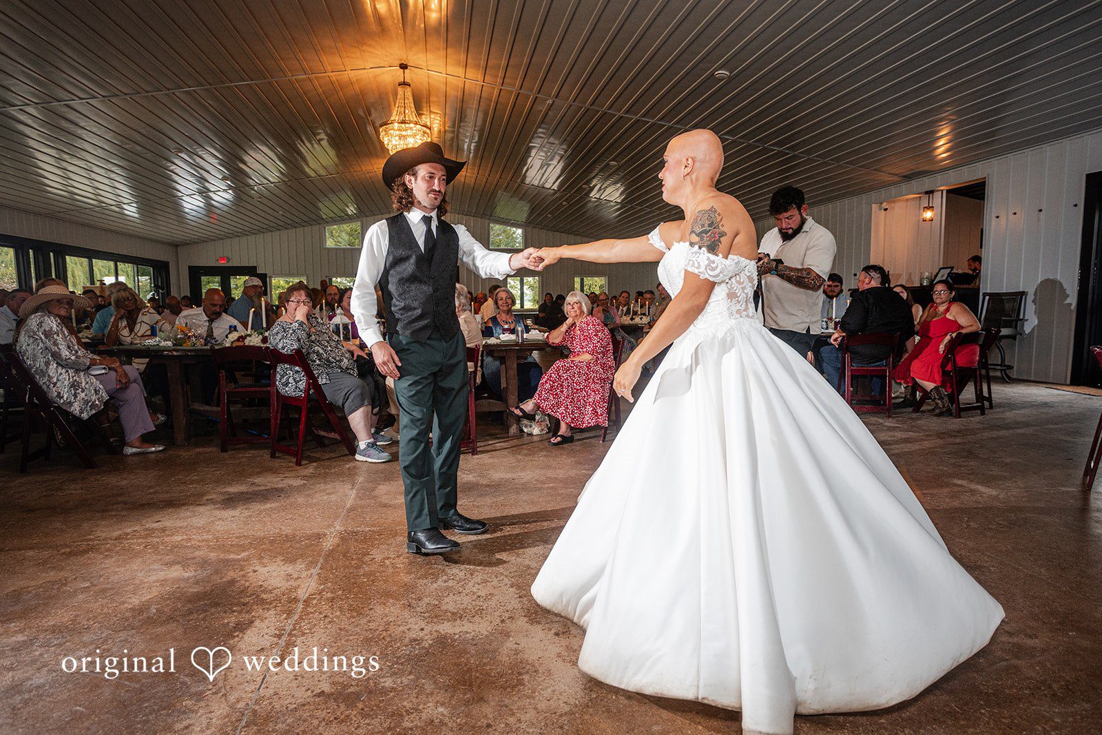 Savannah + Phillip A wide view of a bride and groom dancing on a spacious wooden dance floor inside a reception hall.