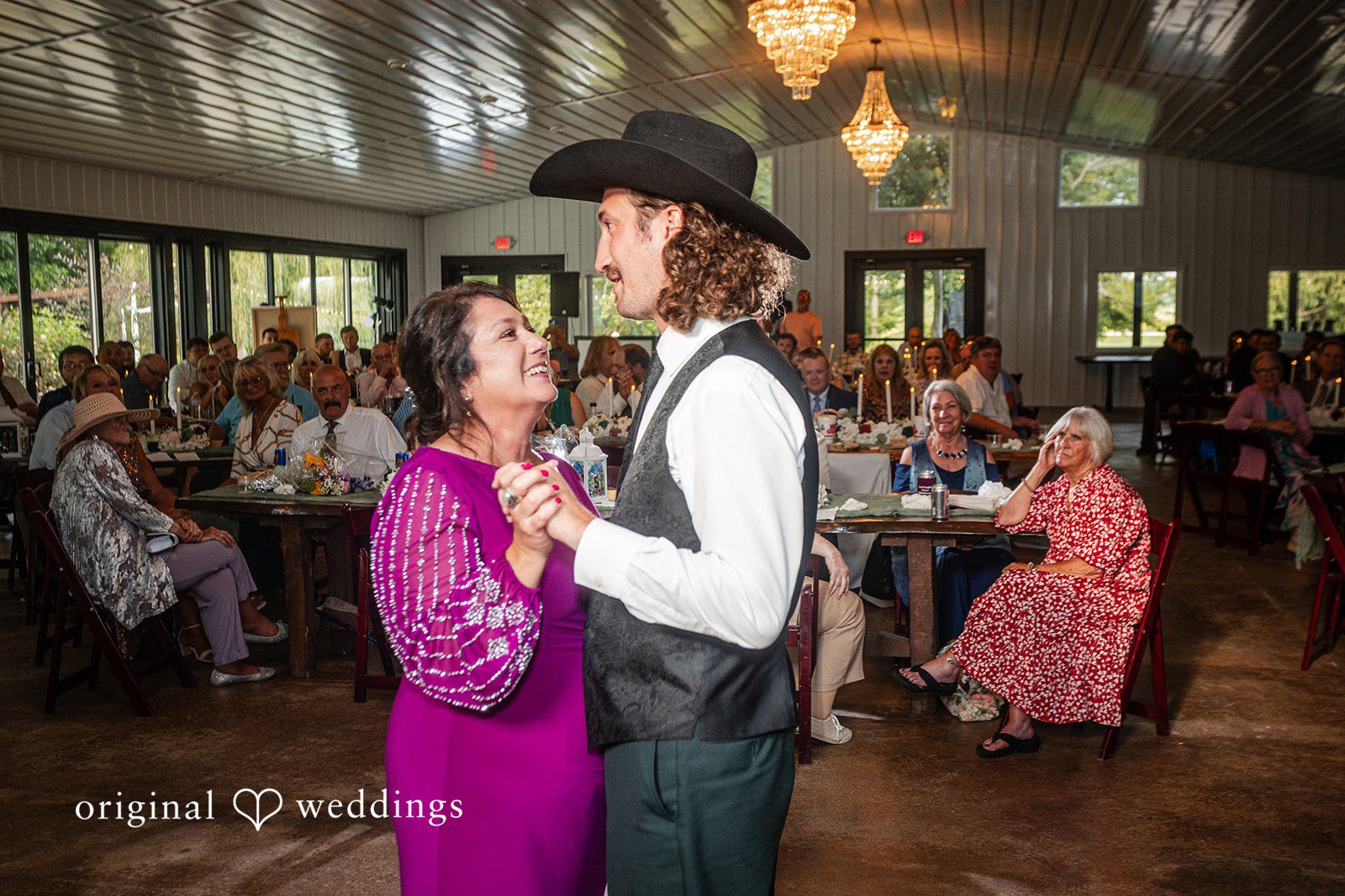 Savannah + Phillip A groom in a vest and cowboy hat dancing with a woman in a purple dress at the reception.