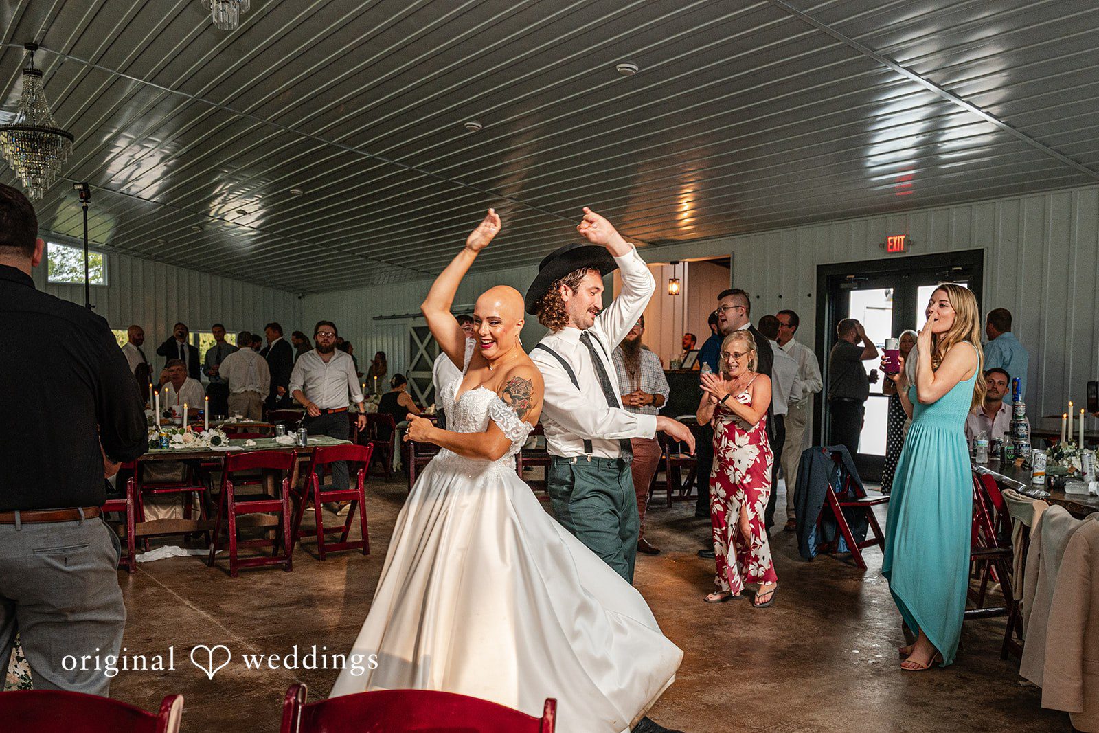 Savannah + Phillip A bride and groom dancing energetically with their hands raised on the reception dance floor.