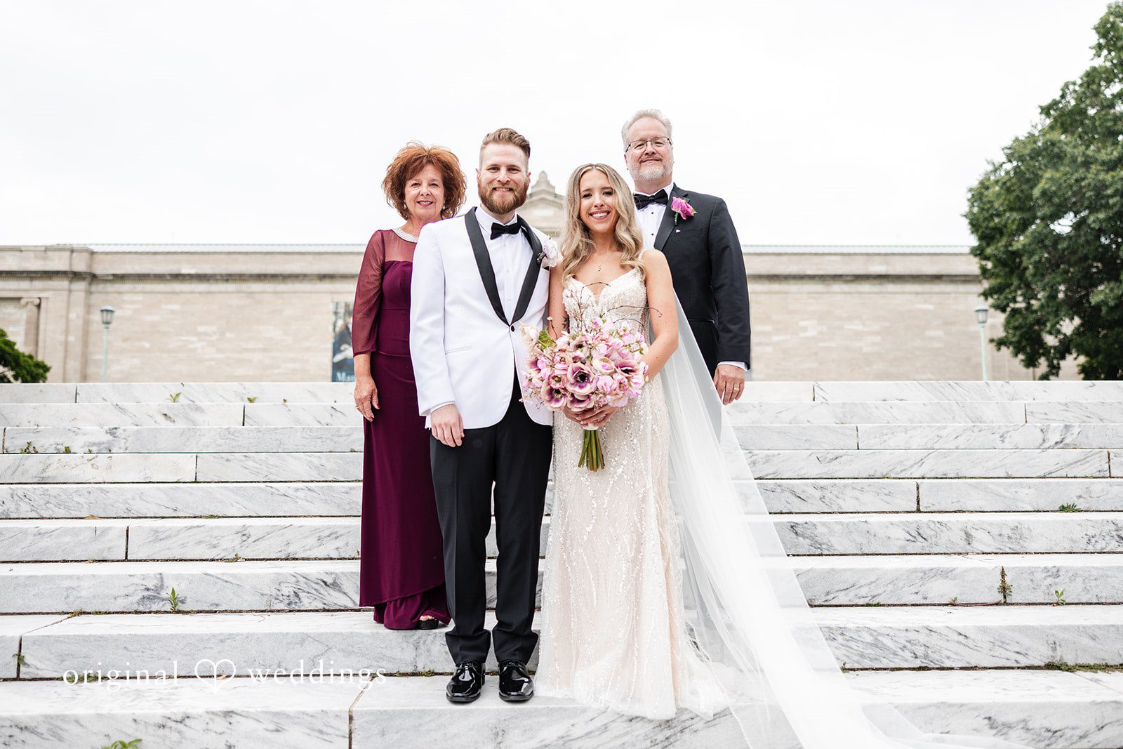 Dan + Alex A bride and groom posing with two members on stone steps.