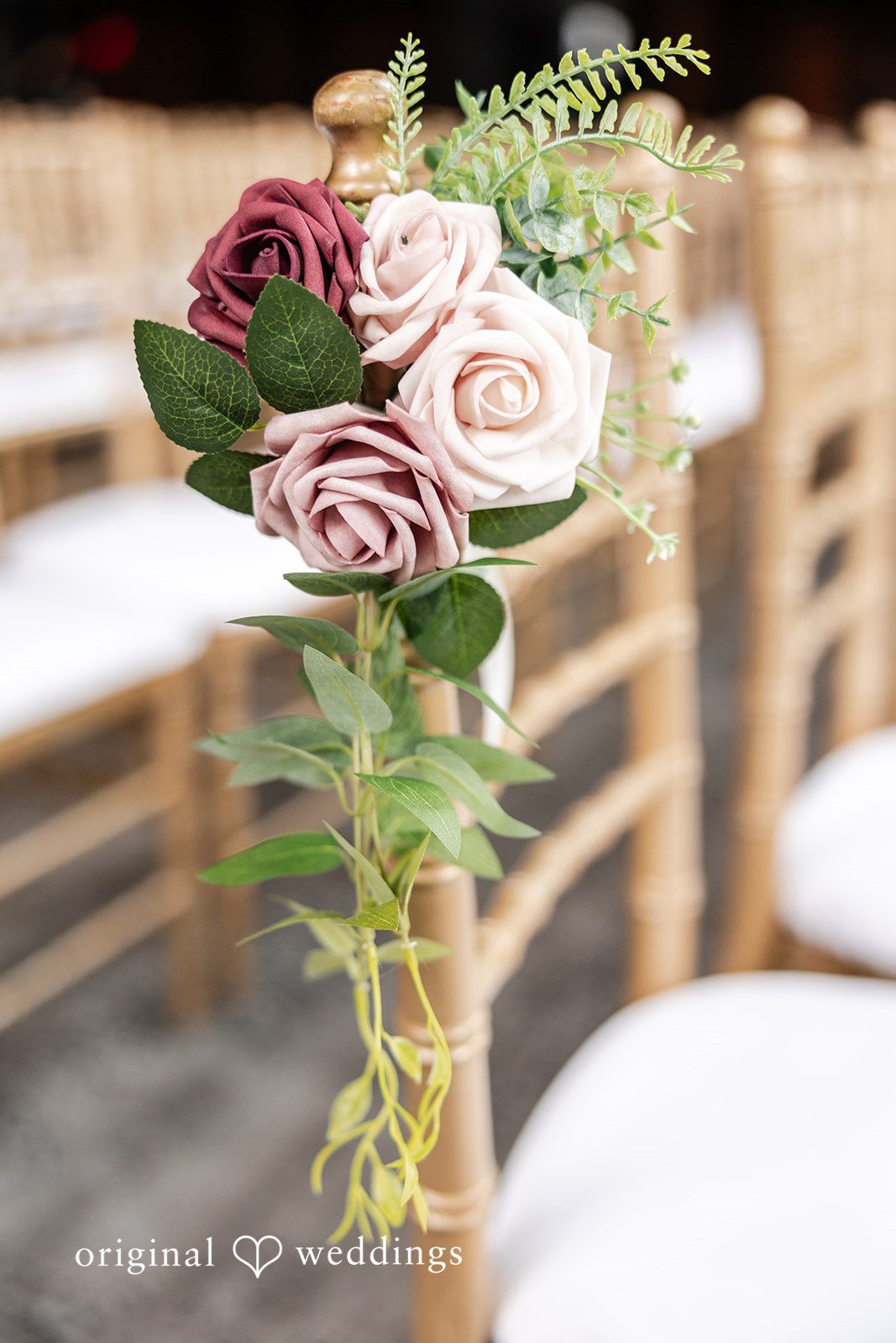 Dan + Alex A close-up of a floral arrangement featuring pink and cream roses tied to a wooden chair.