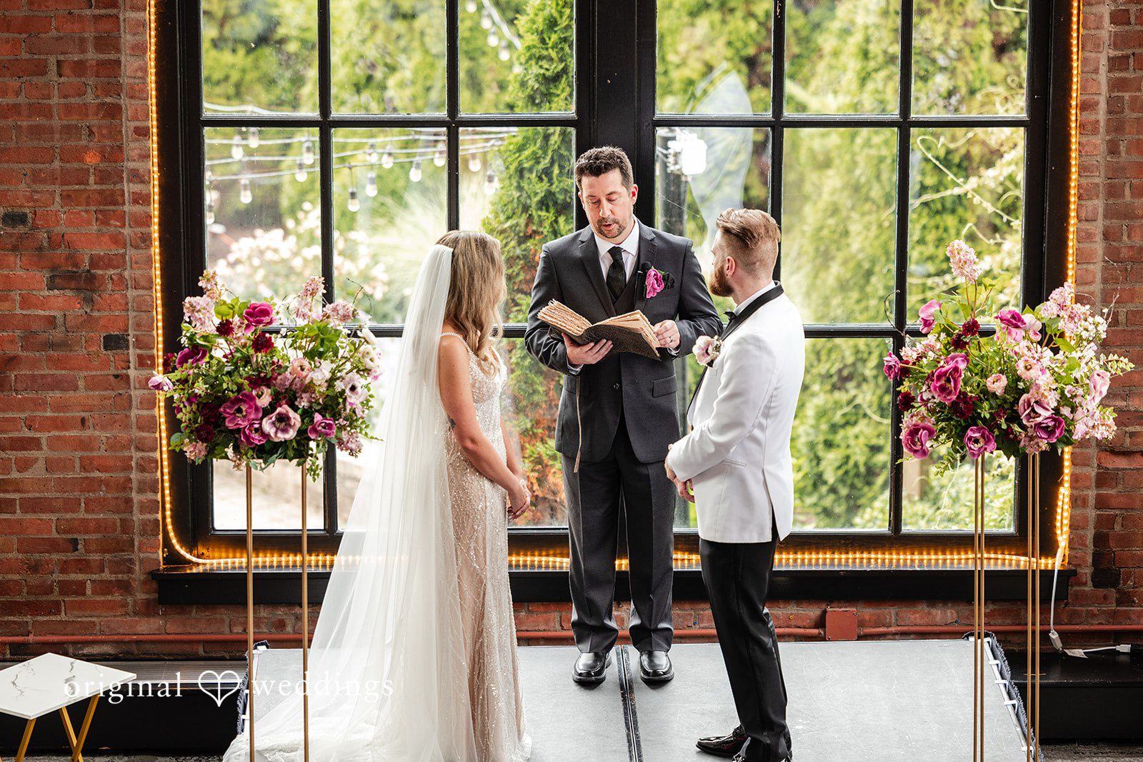 Dan + Alex A bride and groom standing before an officiant in front of a massive iron-framed window.