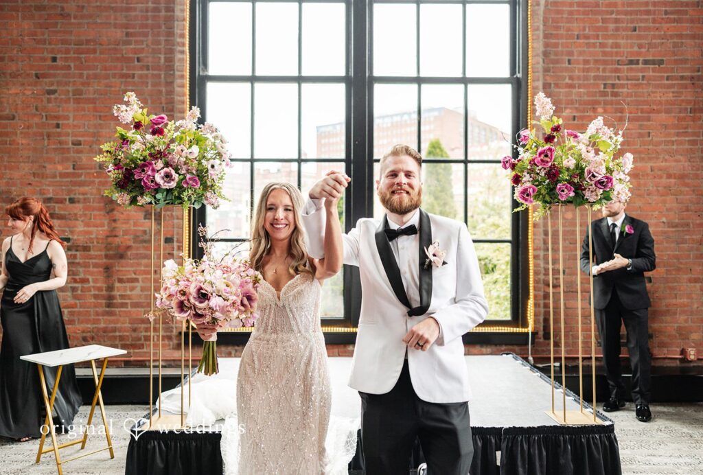 Dan + Alex A bride and groom holding hands and smiling at their wedding altar at Windows on the River captured by Cleveland Wedding Photographers from Original Wedding.