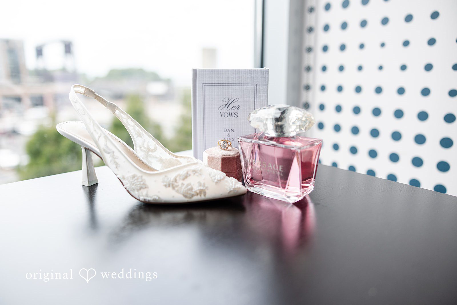 Dan + Alex A pair of white high heels and a perfume bottle sitting on a reflective surface.