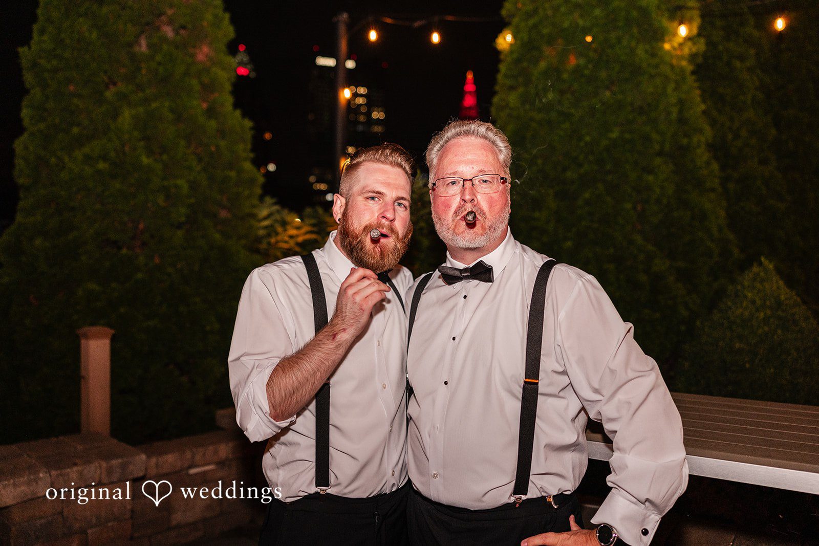 Dan + Alex Two men in suspenders and dress shirts smiling and cheering during a party.